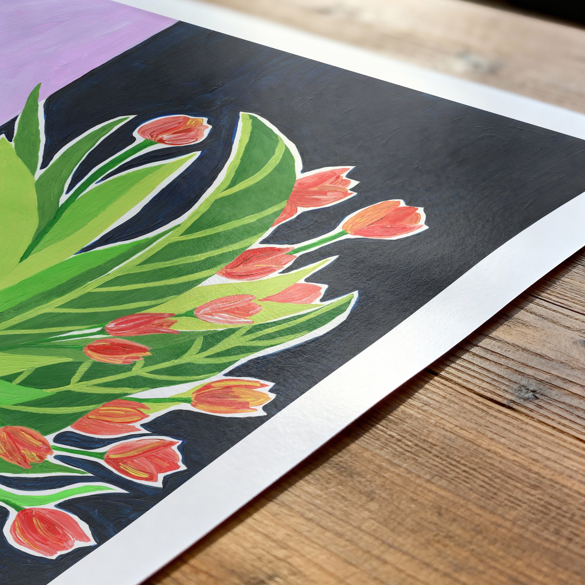 Colorful tulip illustration on a black background with green leaves, placed on a wooden surface.