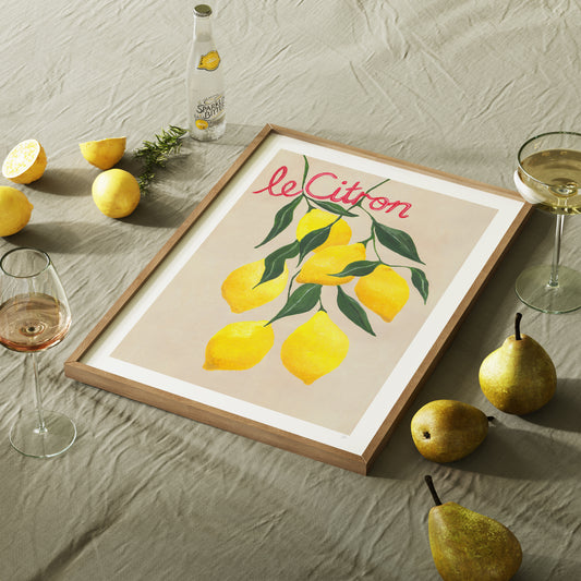 Framed artwork with lemons and 'le Citron' text on a table with lemons and pears.