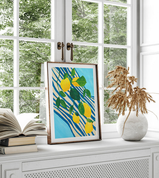 Framed artwork with lemons on a window sill with books and a vase.