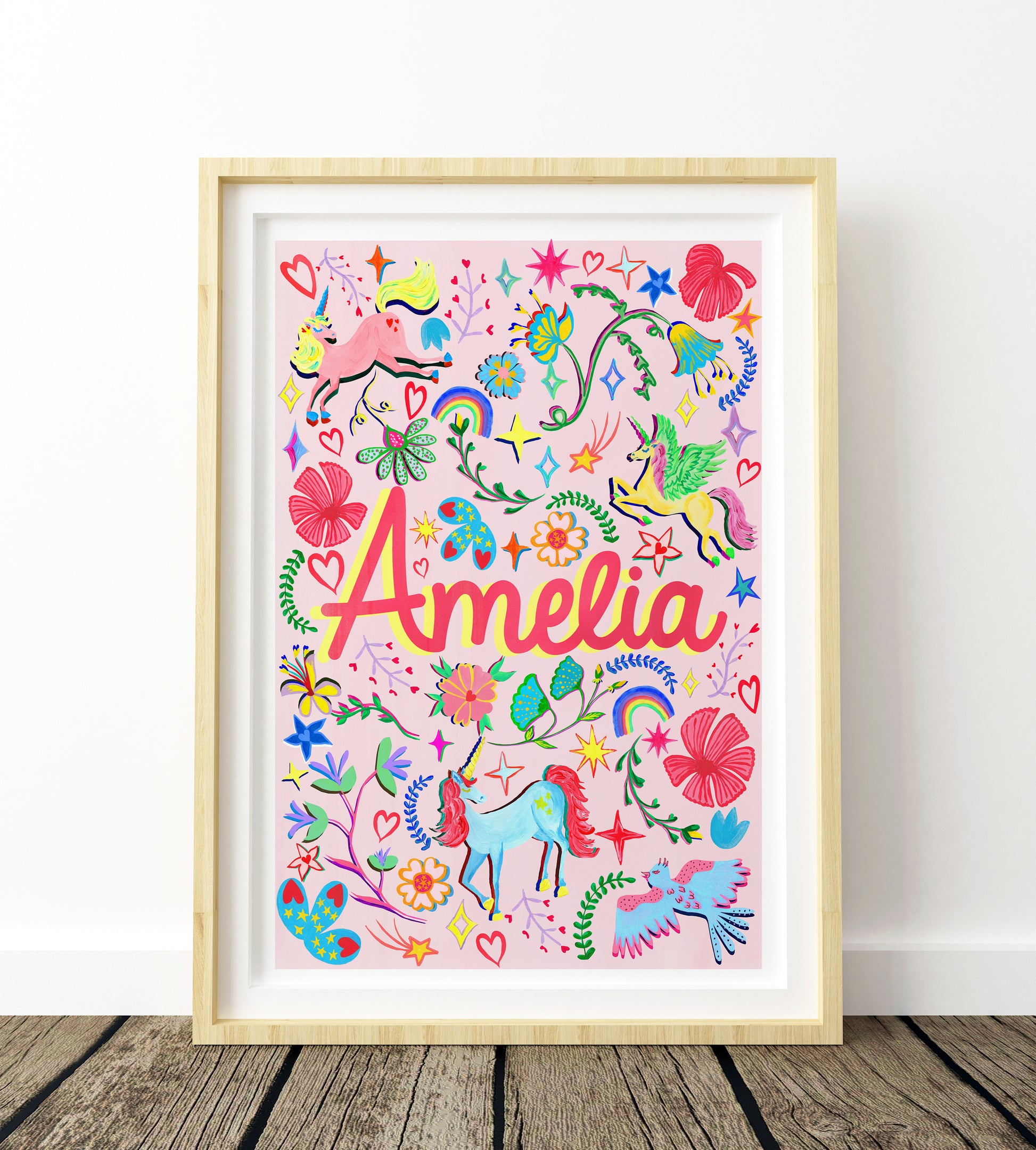 Colorful children's artwork with the name 'Amelia' framed on a white wall.