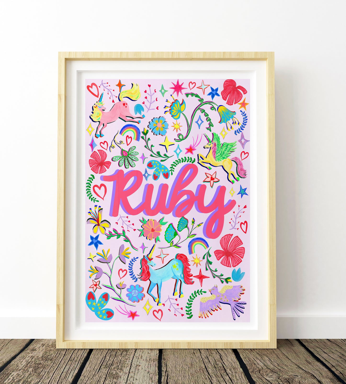 Colorful artwork with 'Ruby' in a wooden frame on a white wall.