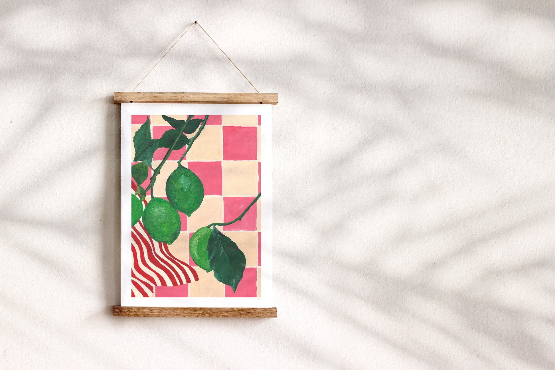Framed artwork of limes set against a pink and cream checkered pattern on a white wall.
