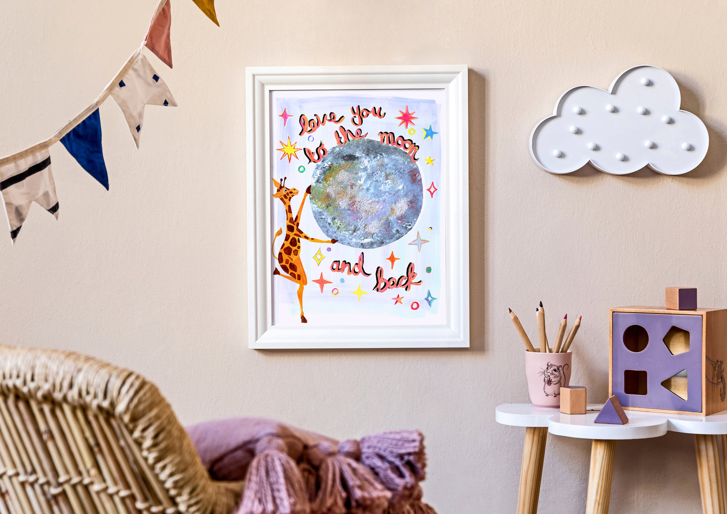 Framed artwork with a giraffe and planet design on a wall in a child's room.