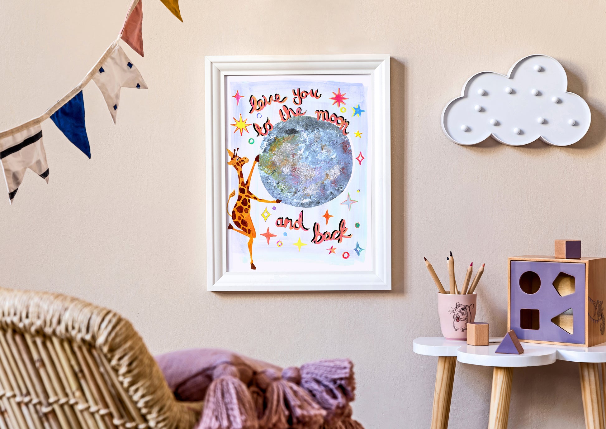 Framed artwork with a giraffe and planet design on a wall in a child's room.