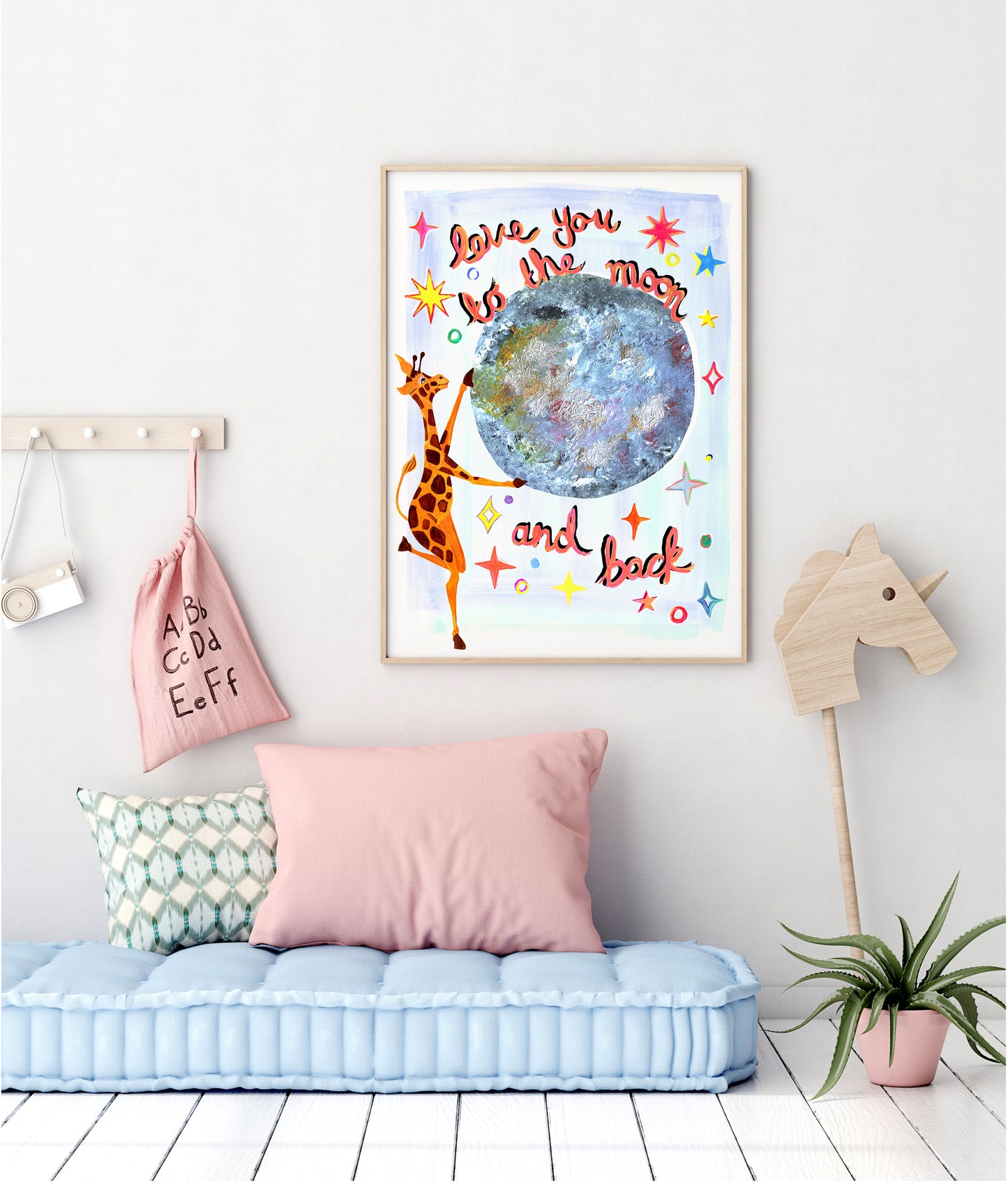 Children's room with a colorful wall art print featuring a giraffe and moon, pink pillow, and blue bench.
