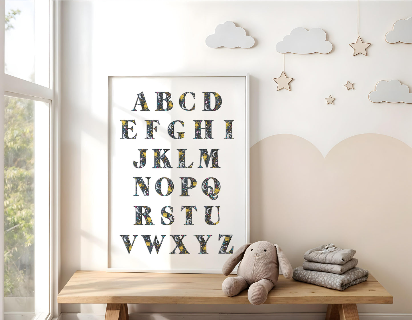Children's room with a framed alphabet poster, teddy bear, and folded blankets on a wooden bench.