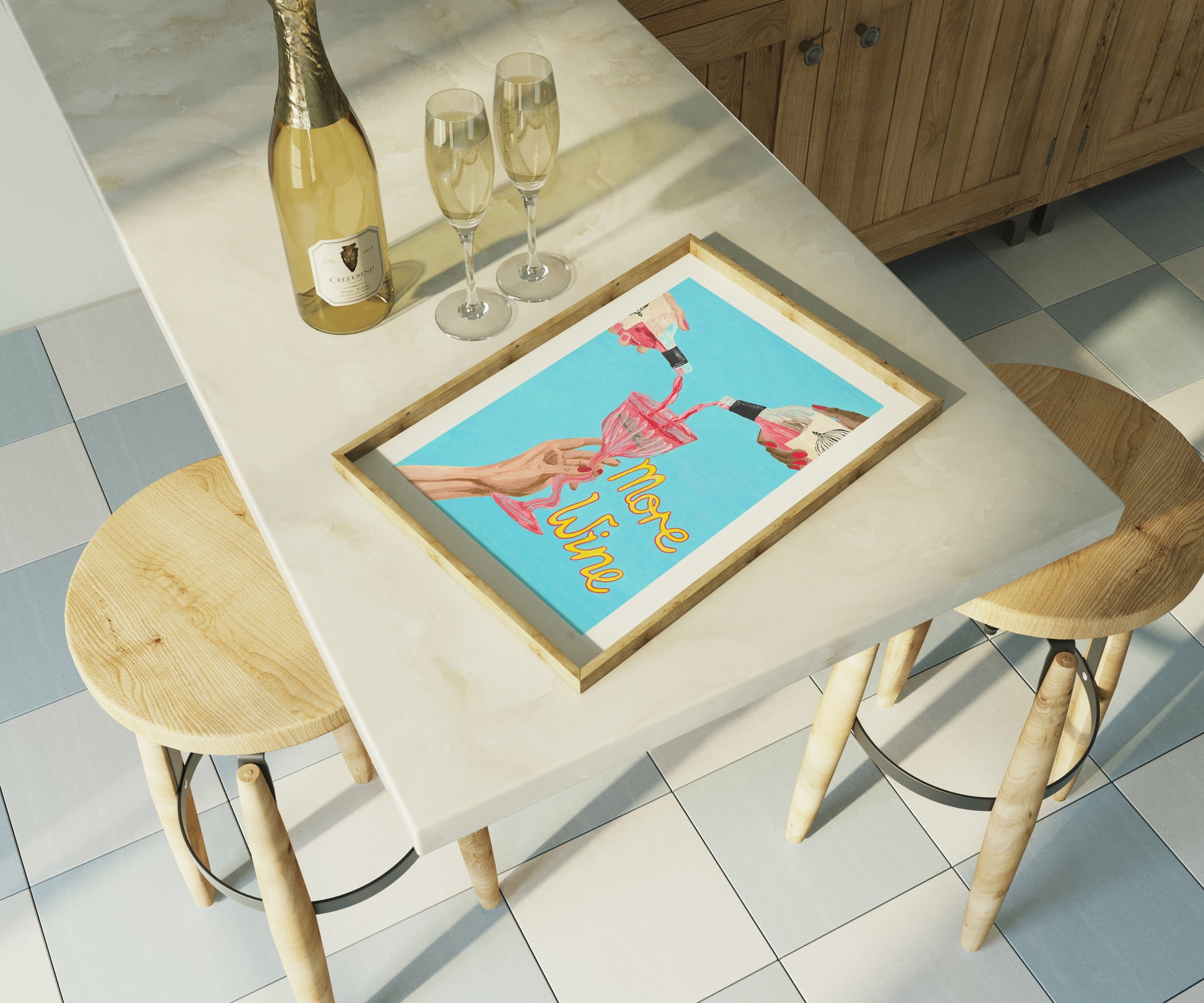Framed artwork on a dining table with champagne and glasses in a kitchen setting