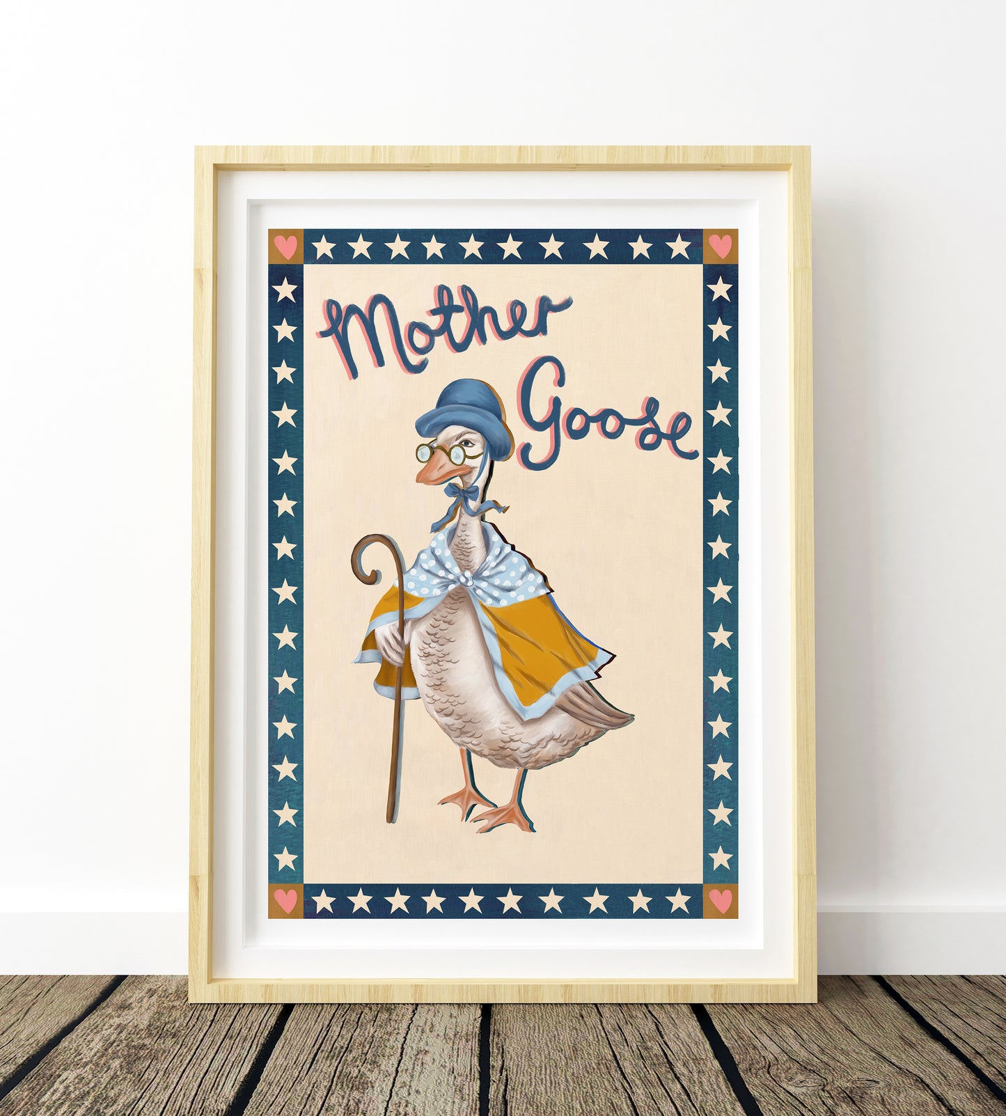 Framed artwork of a goose dressed as Mother Goose with stars and stripes border on a wooden floor.