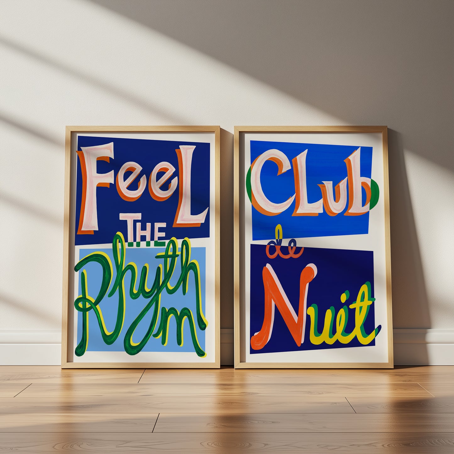 Two framed art pieces with colorful text on a wooden floor.