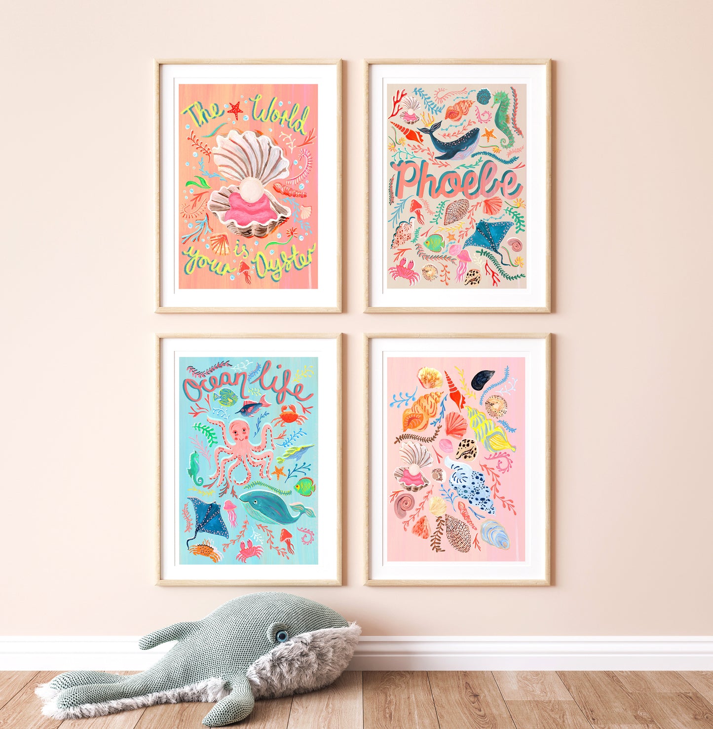 Four framed illustrations on a wall with a plush toy whale at the bottom.
