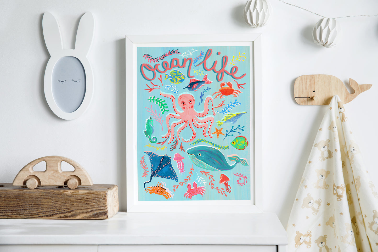 Colorful 'Ocean Life' poster on a white wall with decorative items.