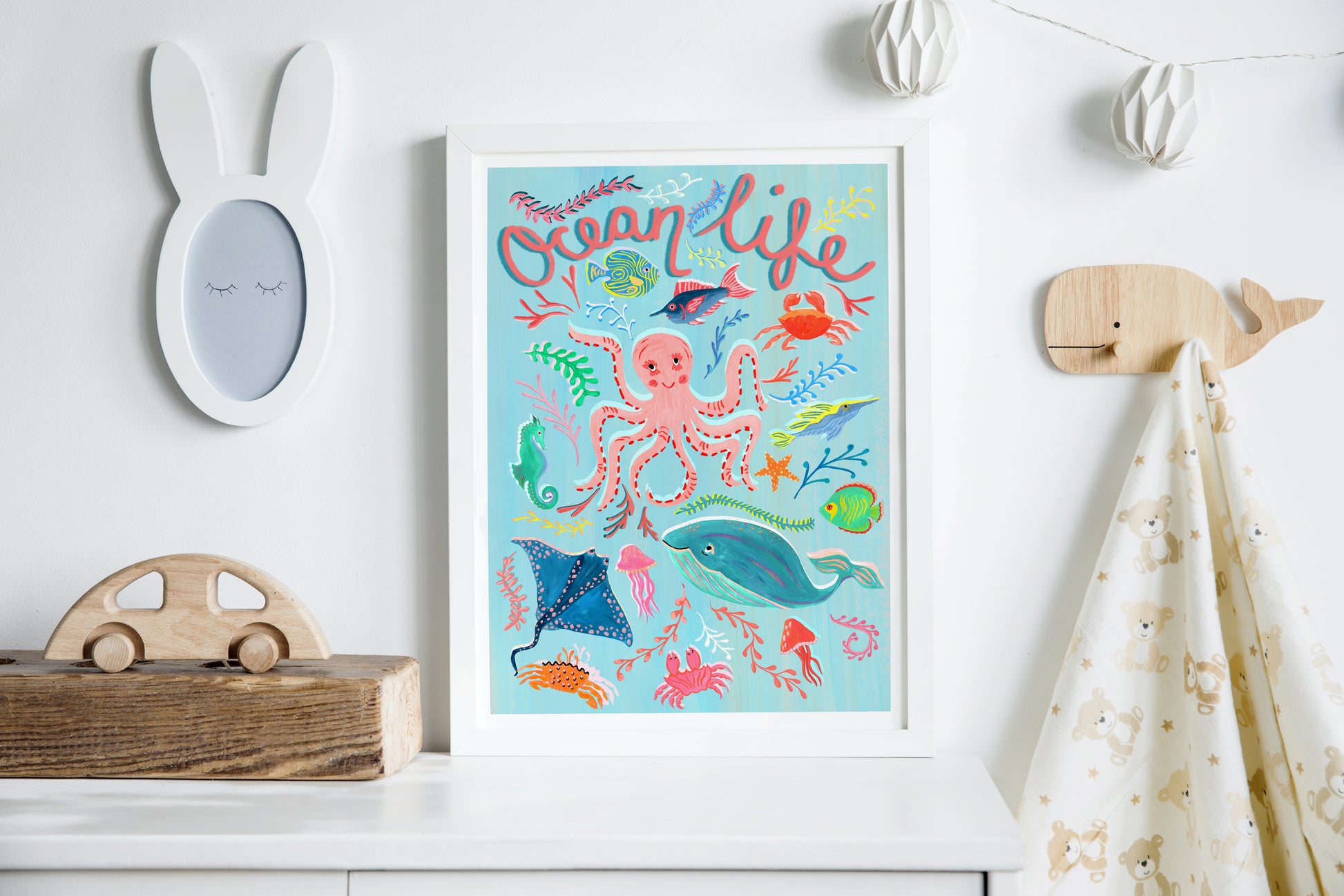 Colorful 'Ocean Life' poster on a white wall with decorative items.