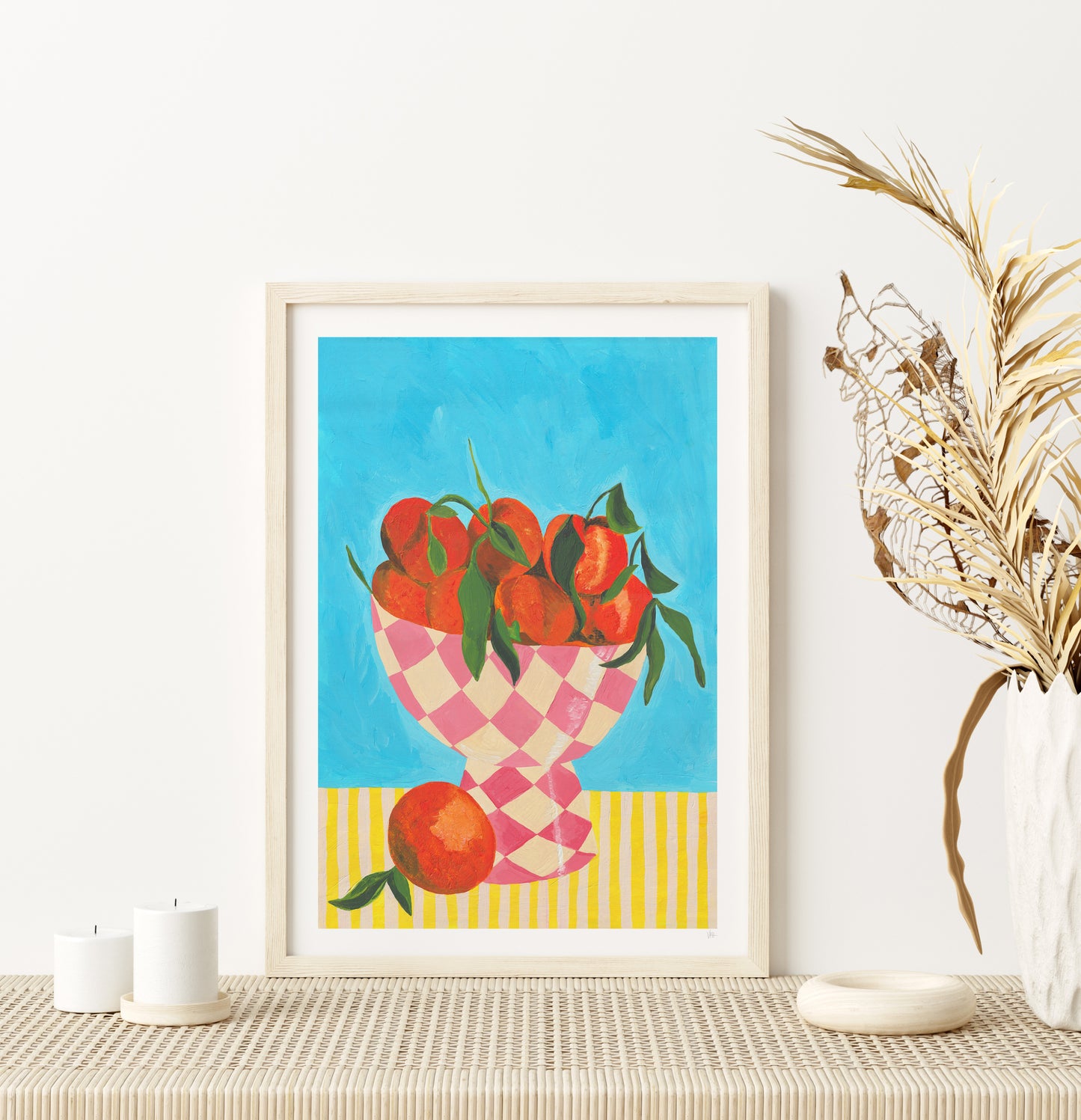 Framed artwork of a checkered bowl with tomatoes on a white wall.