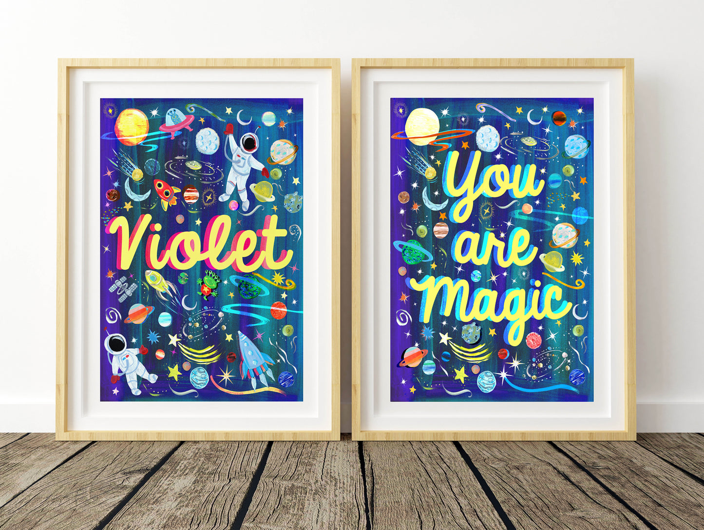 Two framed prints with space-themed designs and motivational text on a wooden floor.