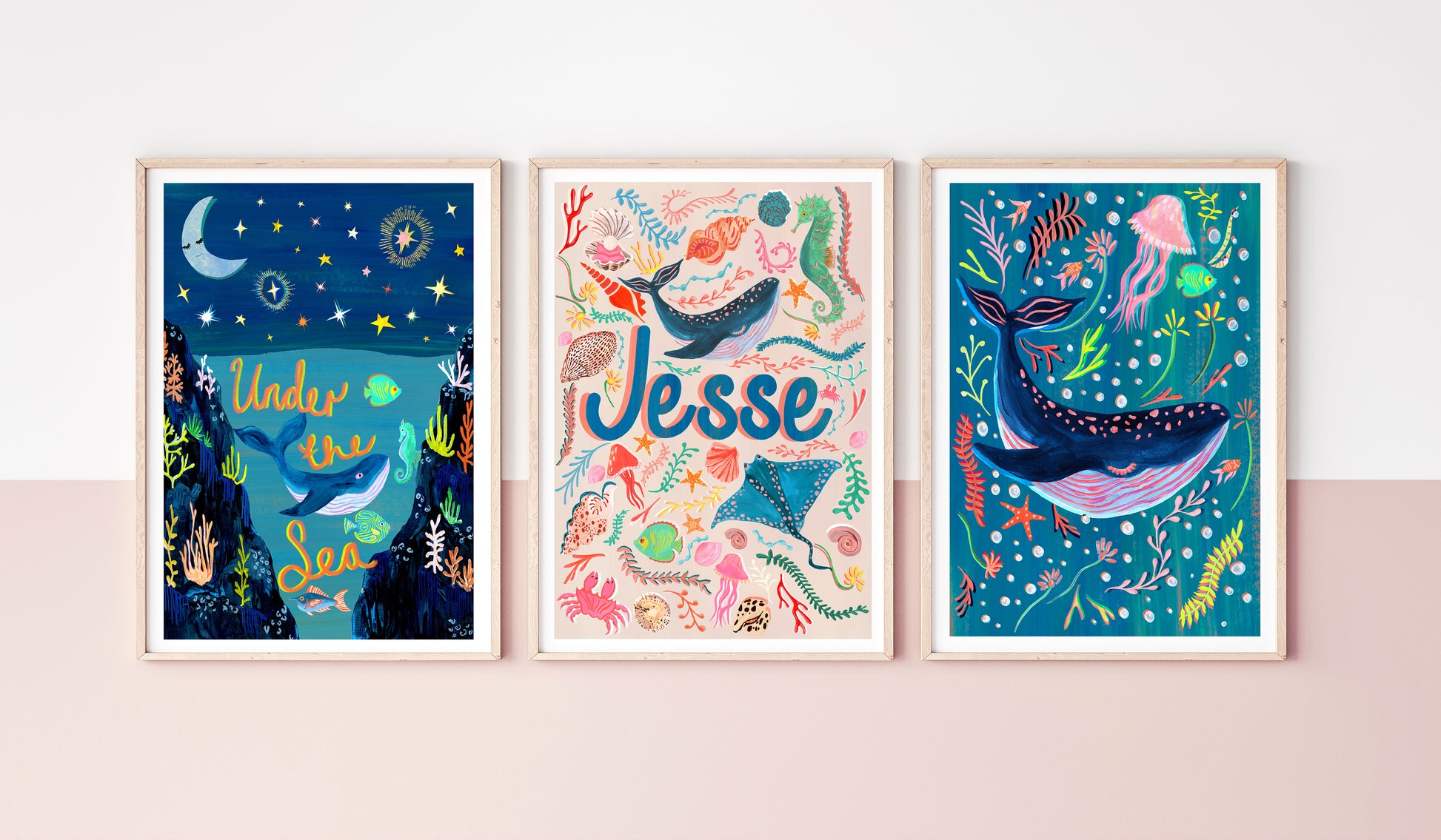 Three framed illustrations of underwater scenes with colorful sea creatures on a light pink wall.