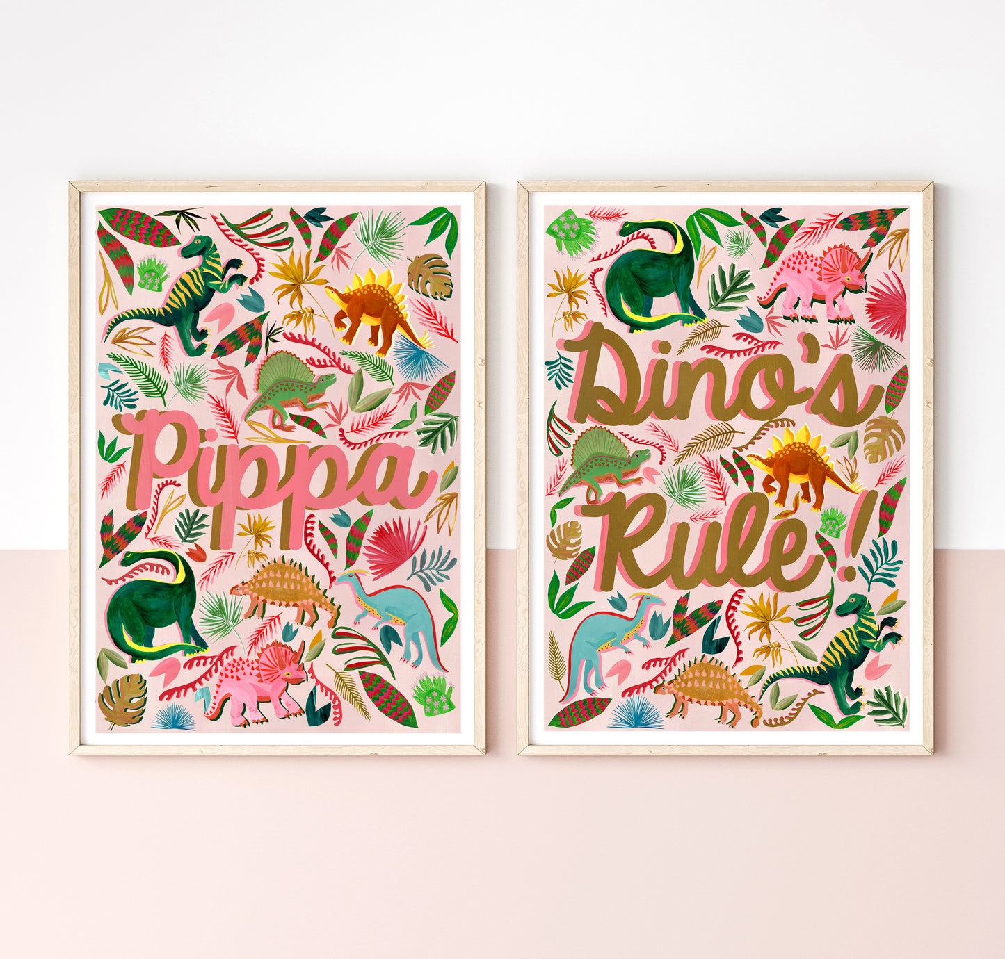 Two framed prints with colorful dinosaur illustrations and text on a white wall.