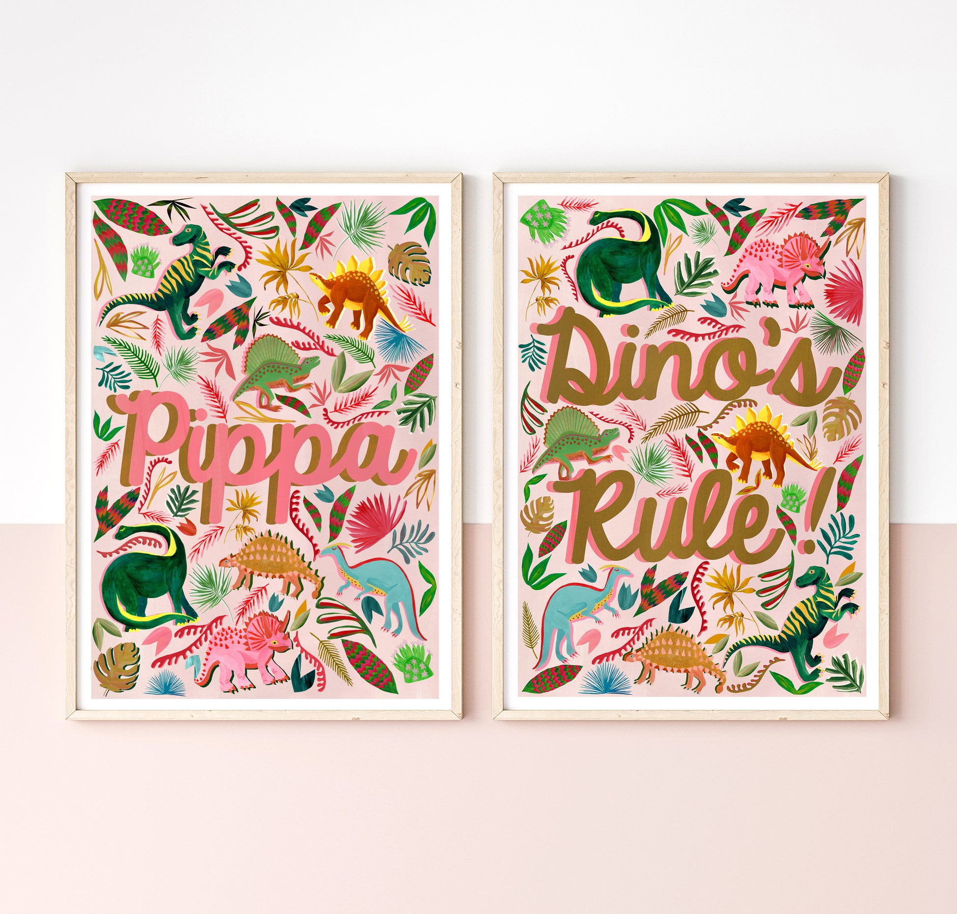 Two framed prints with colorful dinosaur illustrations and text on a white wall.