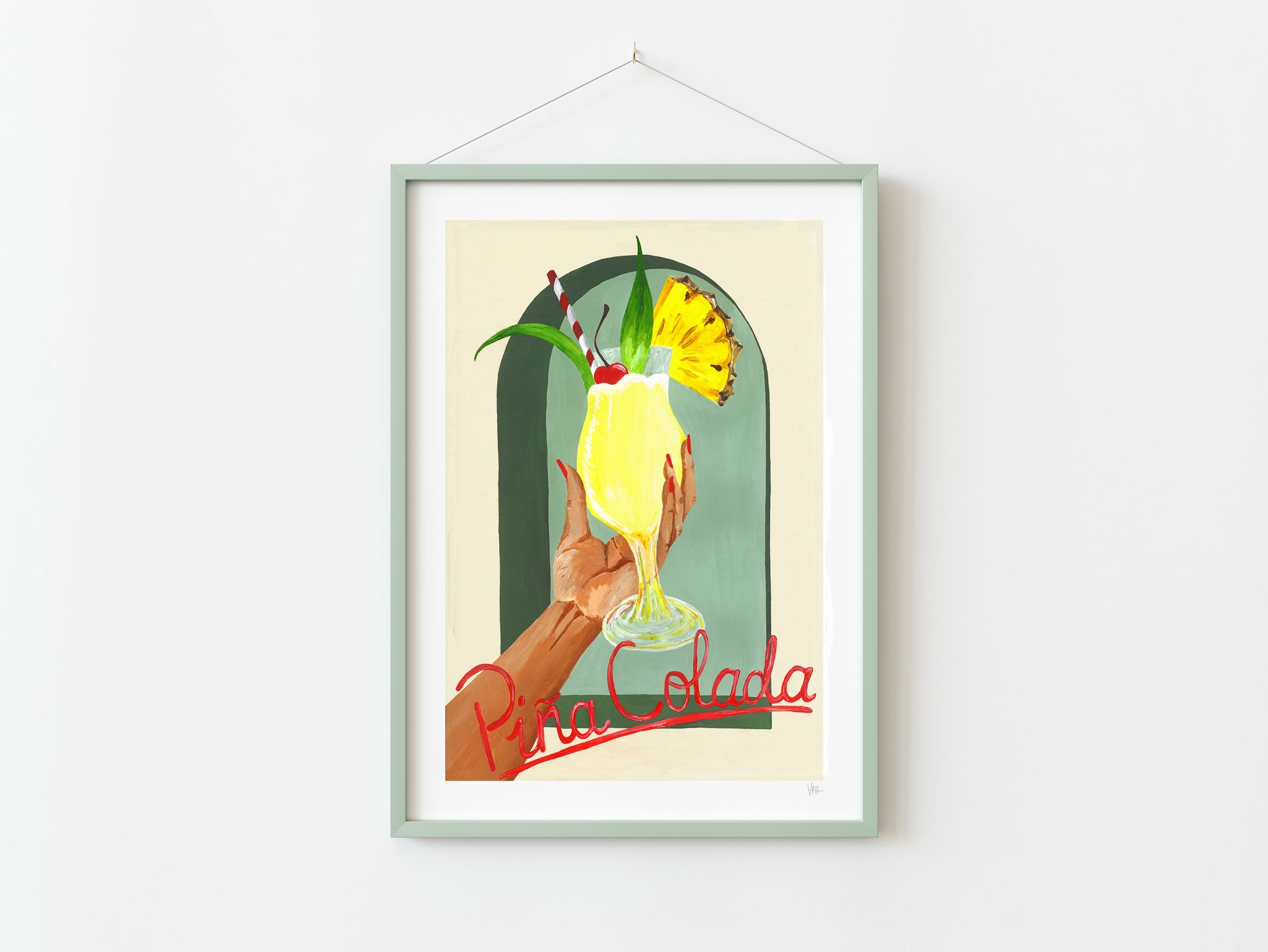 Framed artwork of a hand holding a yellow cocktail with 'Pina Colada' text on a white wall.