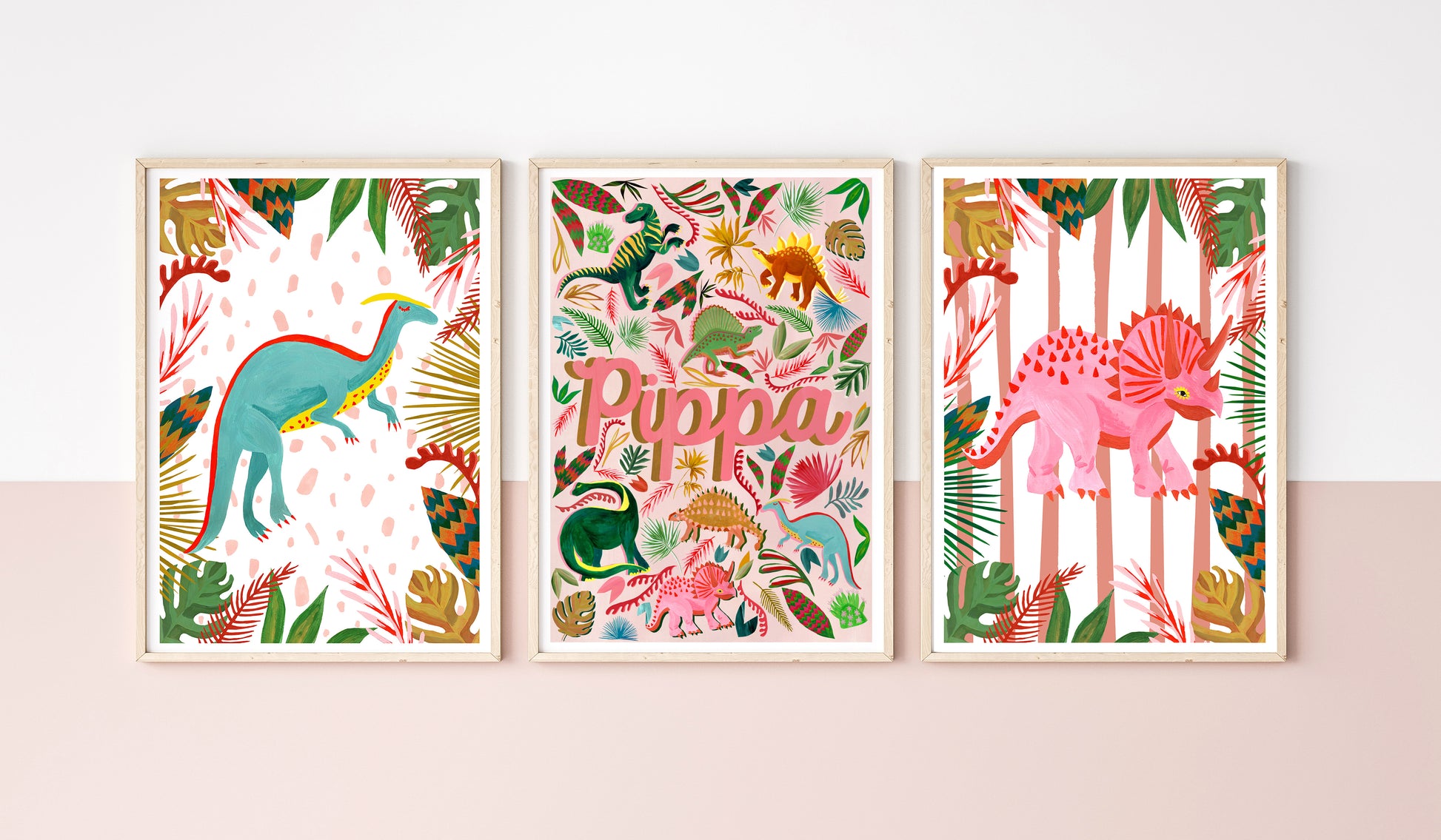 Three colorful dinosaur-themed prints on a white wall with a pink baseboard.
