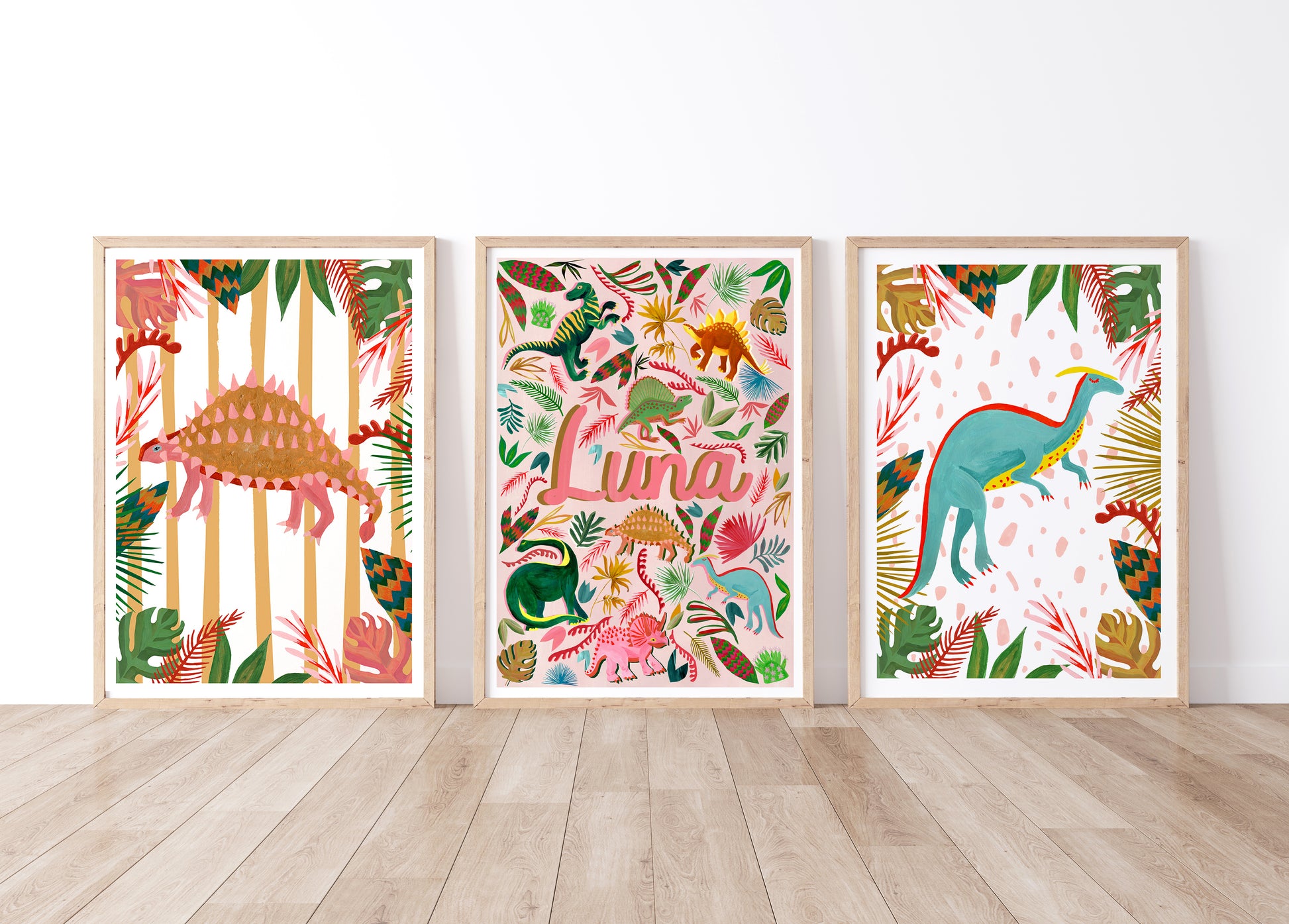 Three framed dinosaur-themed artworks on a white wall with wooden floor.