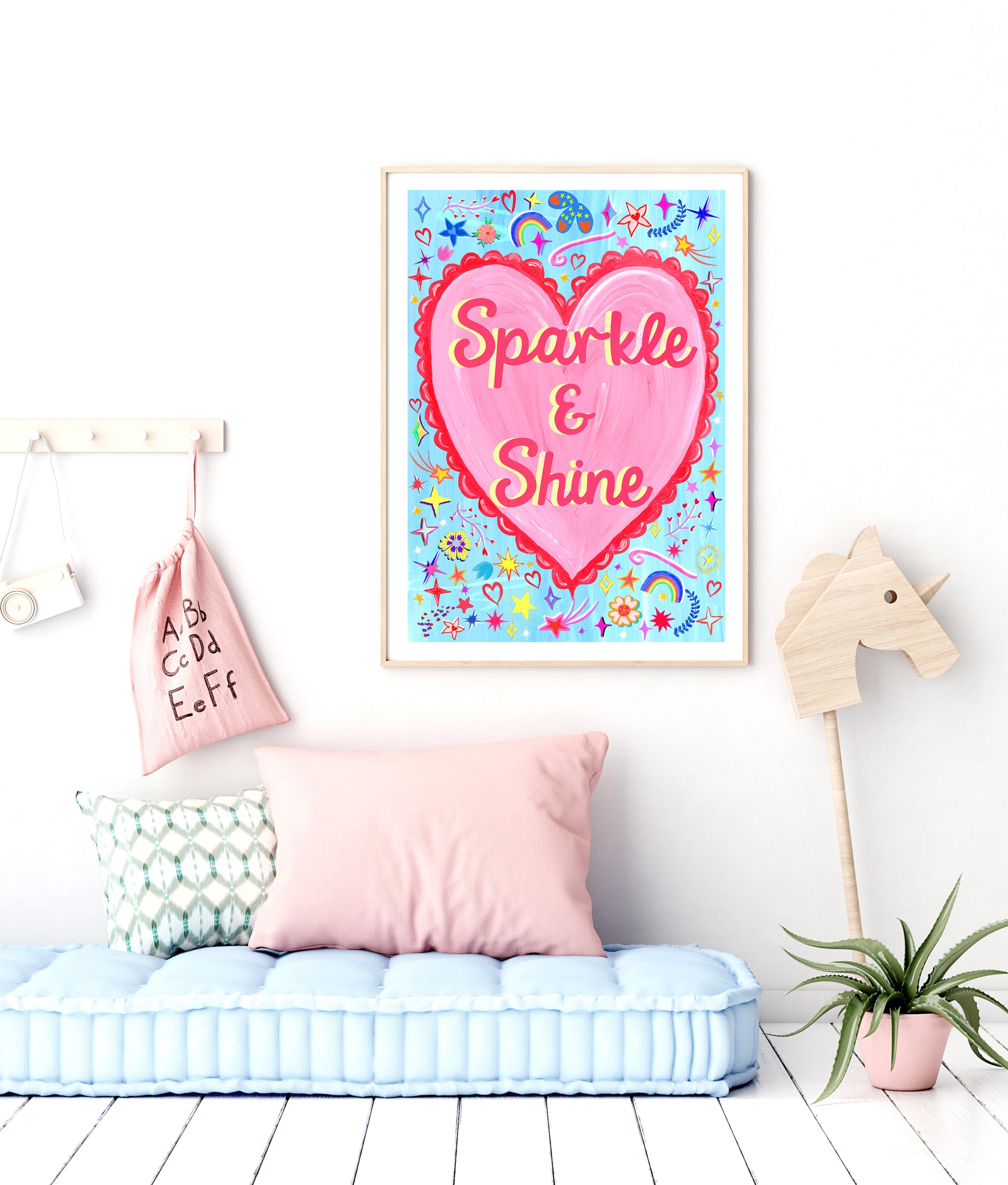 Children's room with a heart-shaped poster reading 'Sparkle & Shine', pink pillow, and decorative items.