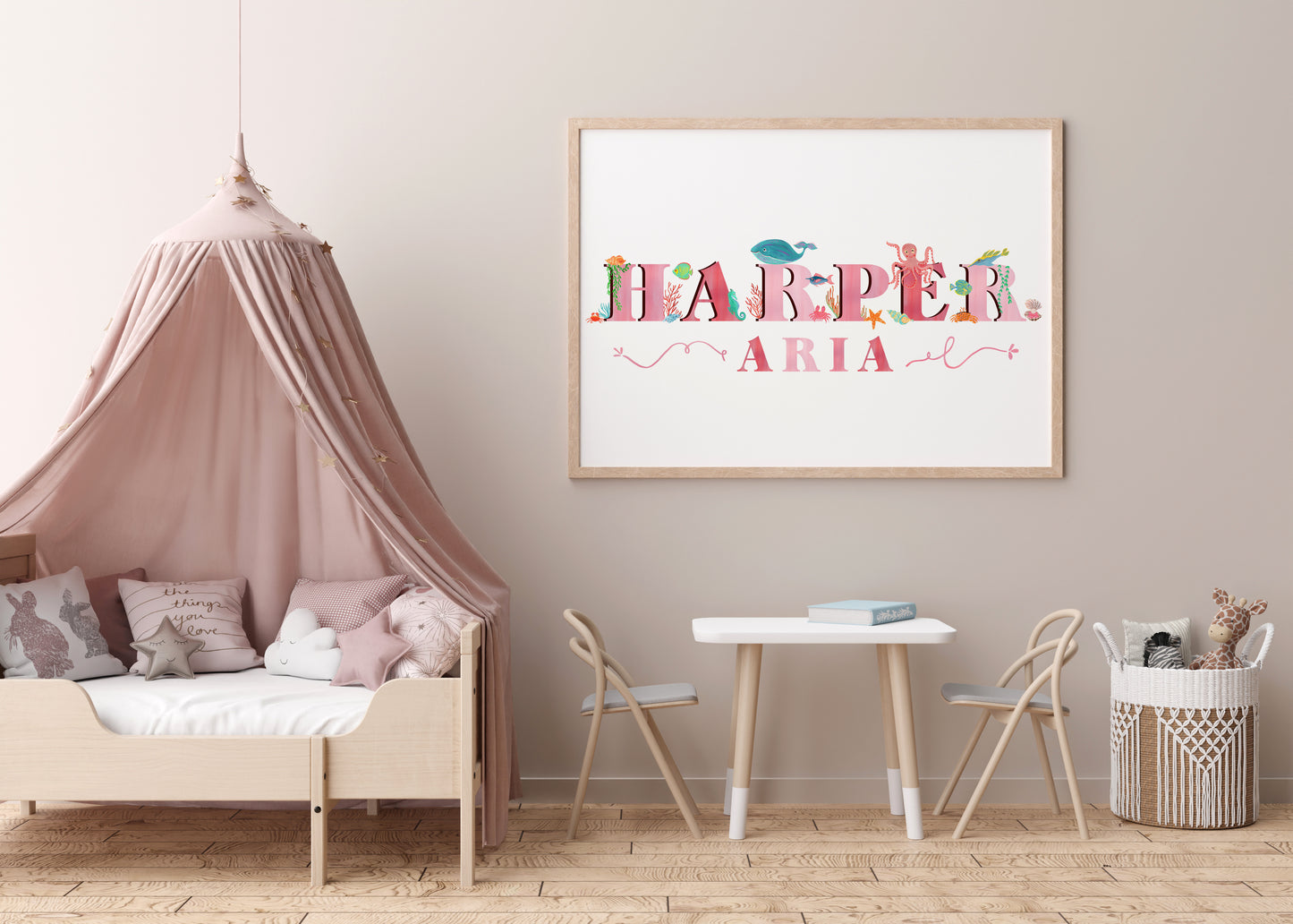 Children's room with a bed, table, chairs, and a framed name art piece with  sea animal illustrations on the wall.