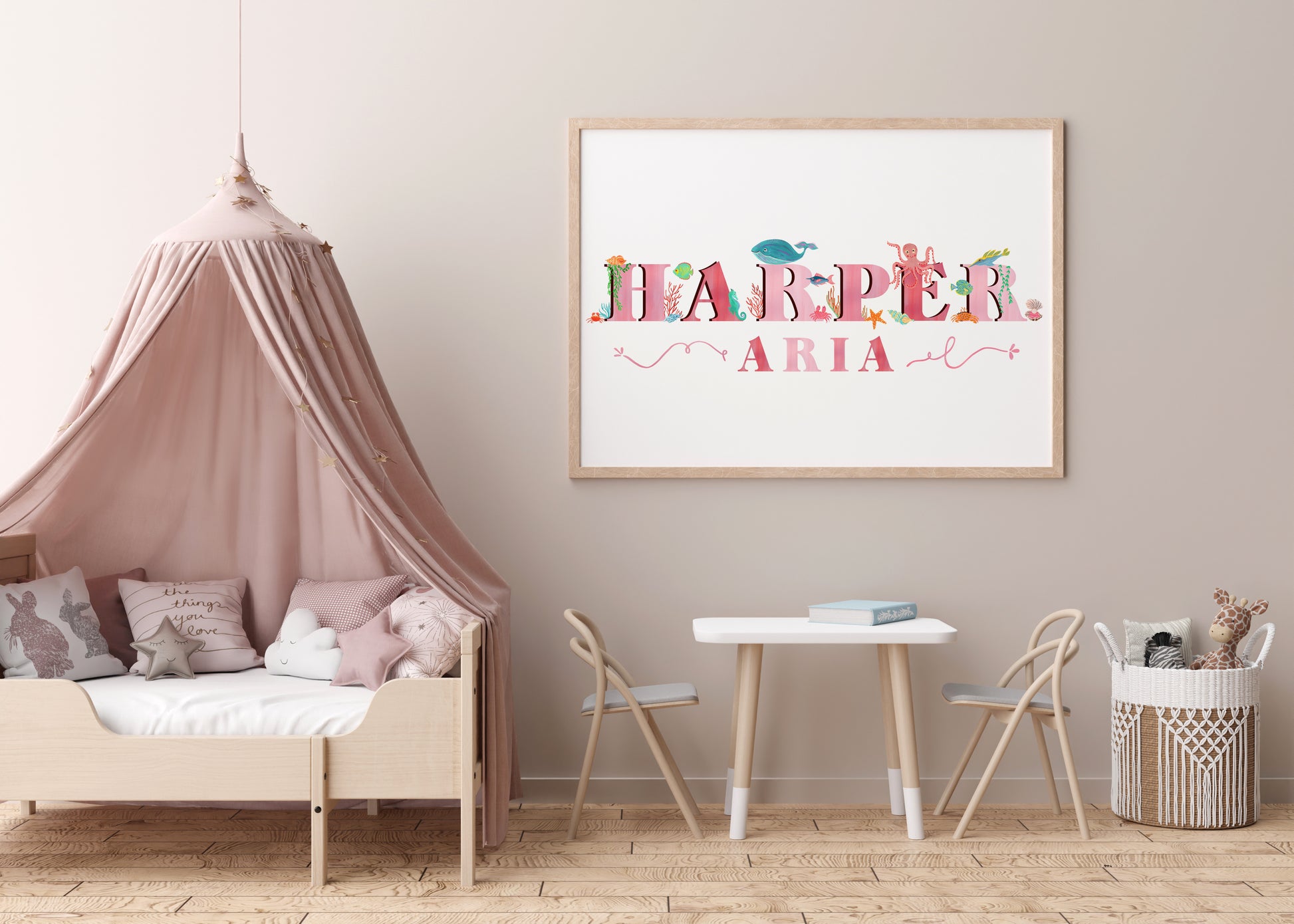 Children's room with a bed, table, chairs, and a framed name art piece with  sea animal illustrations on the wall.