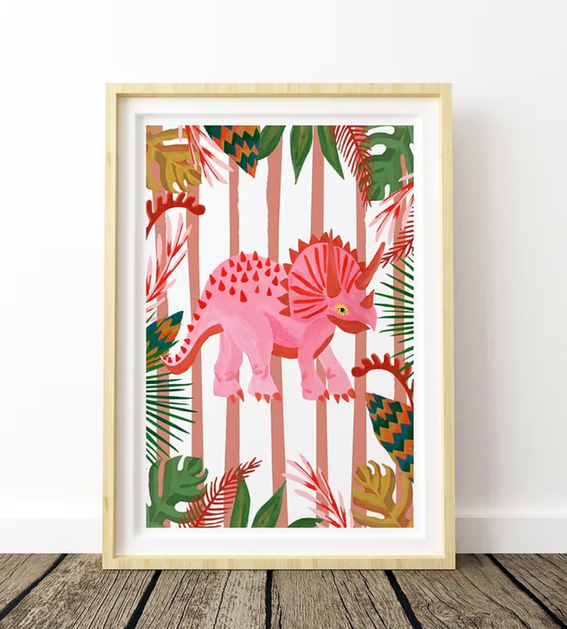 Framed artwork with a pink dinosaur and tropical leaves on a white background