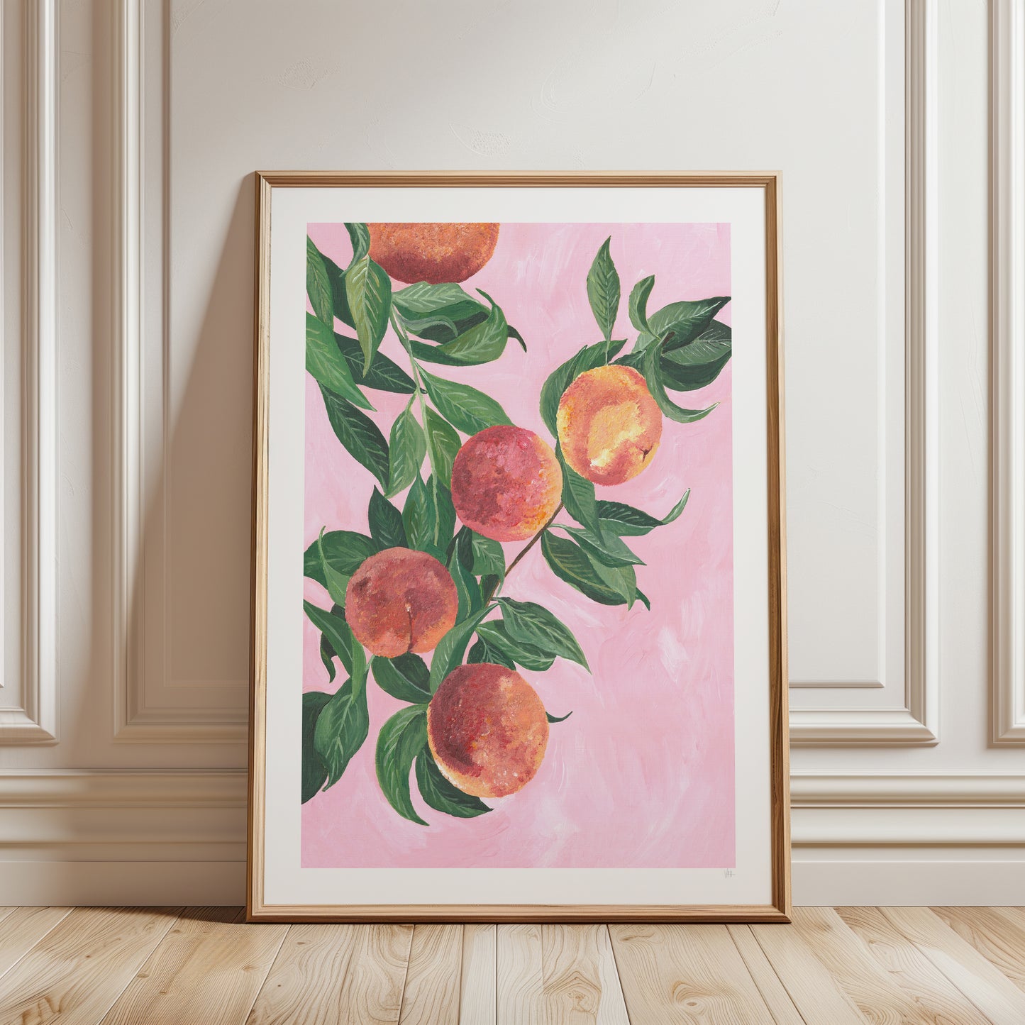 Framed artwork of peaches on a pink background in a room with wooden floor and white walls.