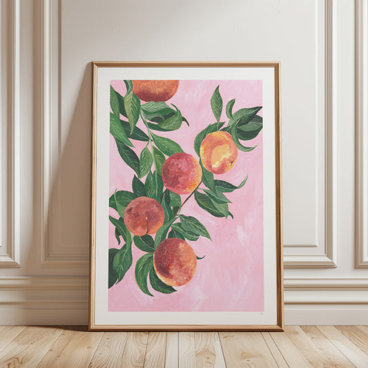 Framed artwork of peaches on a pink background in a room with wooden floor and white walls.