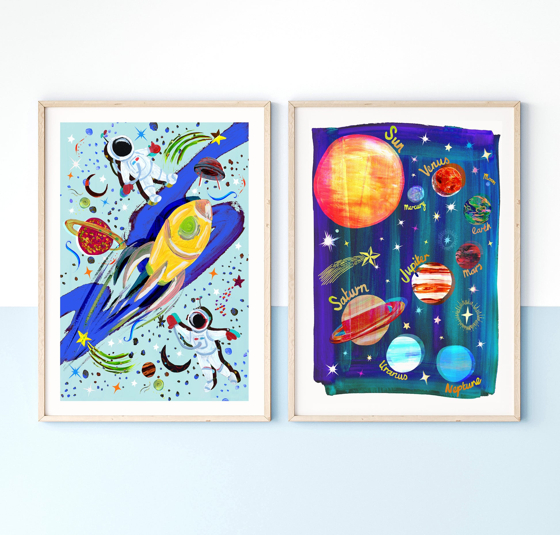 Two framed space-themed artworks on a light blue wall.