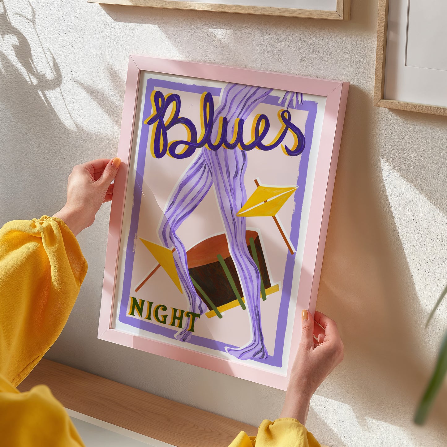Person holding a framed artwork with 'Blues Night' text and abstract design.