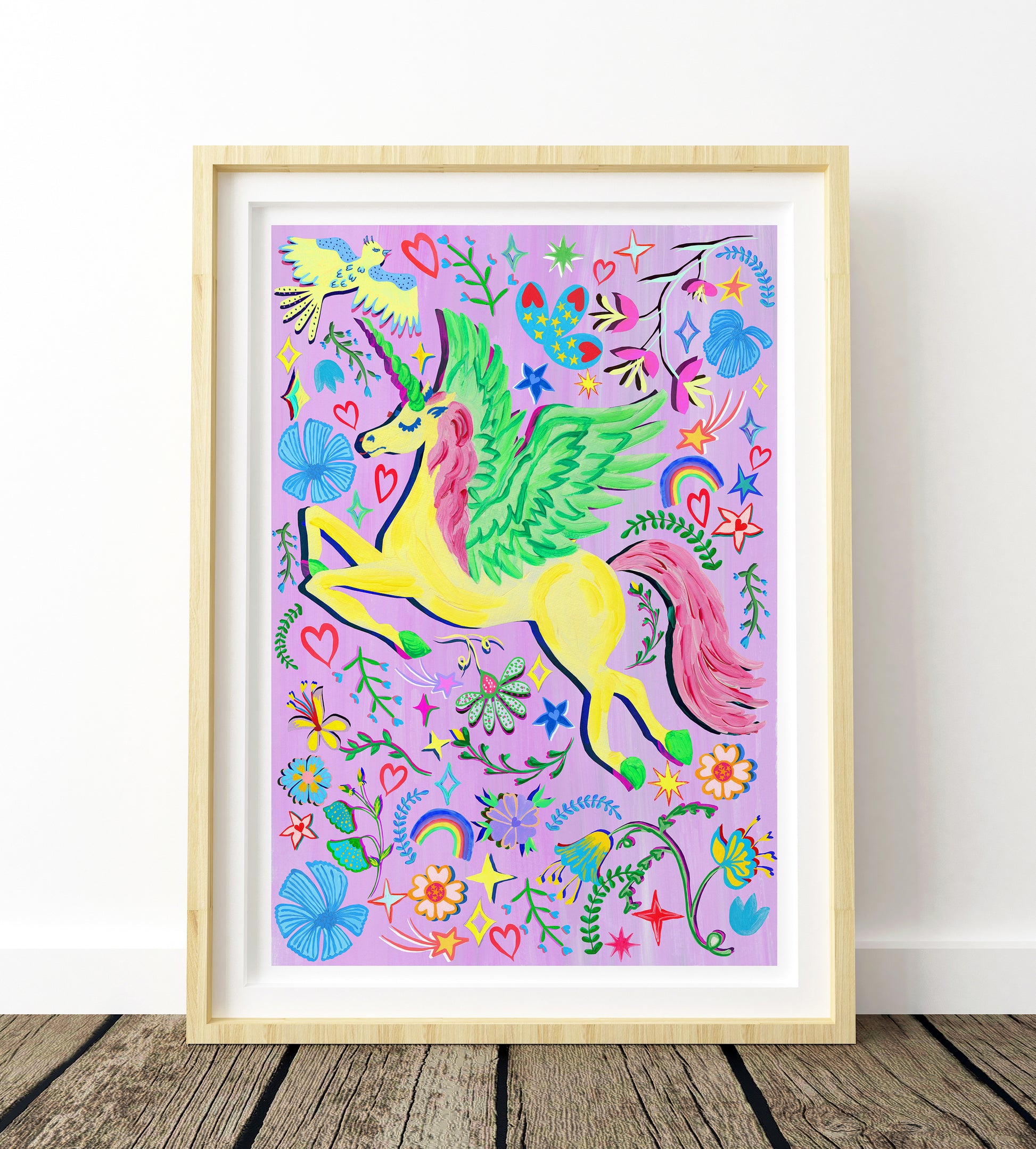 A colouful yellow unicorn painting place against a purple bacground and surrounded by flower and rainbow illustrations in a light wood frame.