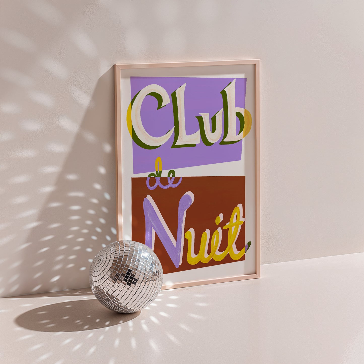 Framed artwork with 'Club de Nuit' text next to a disco ball on a light surface.