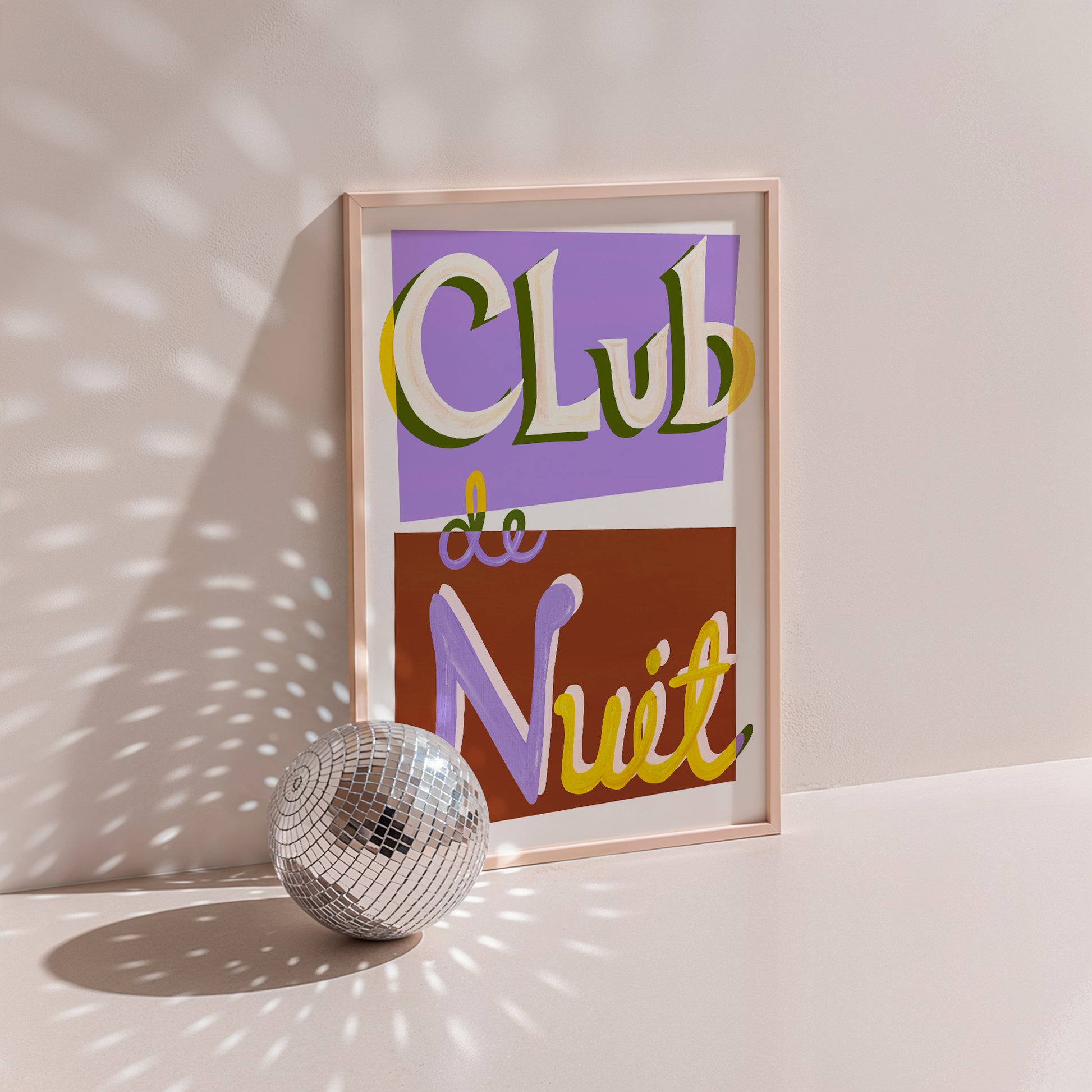 Framed artwork with 'Club de Nuit' text next to a disco ball on a light surface.