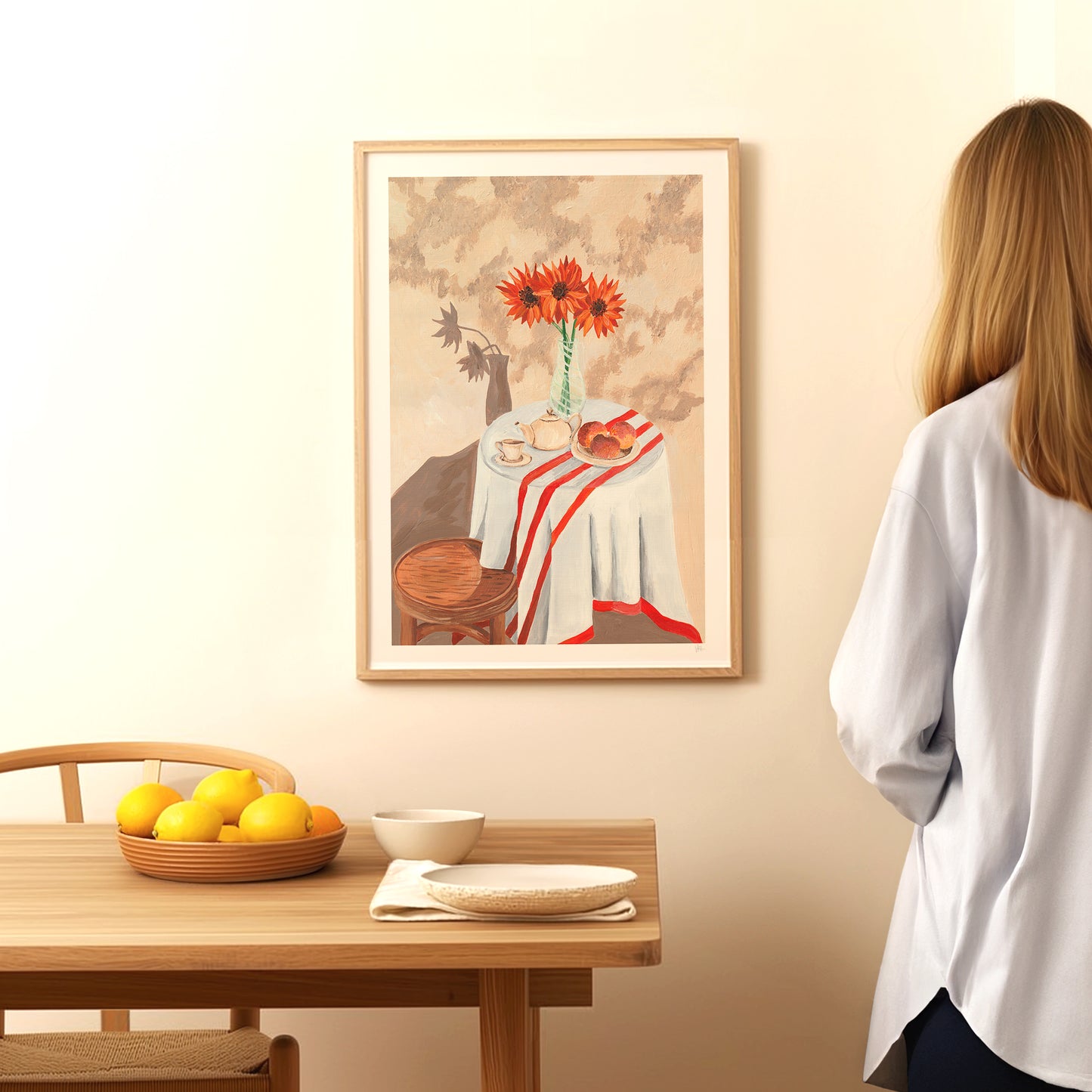 Woman looking at a framed painting of a still life scene on a wall.