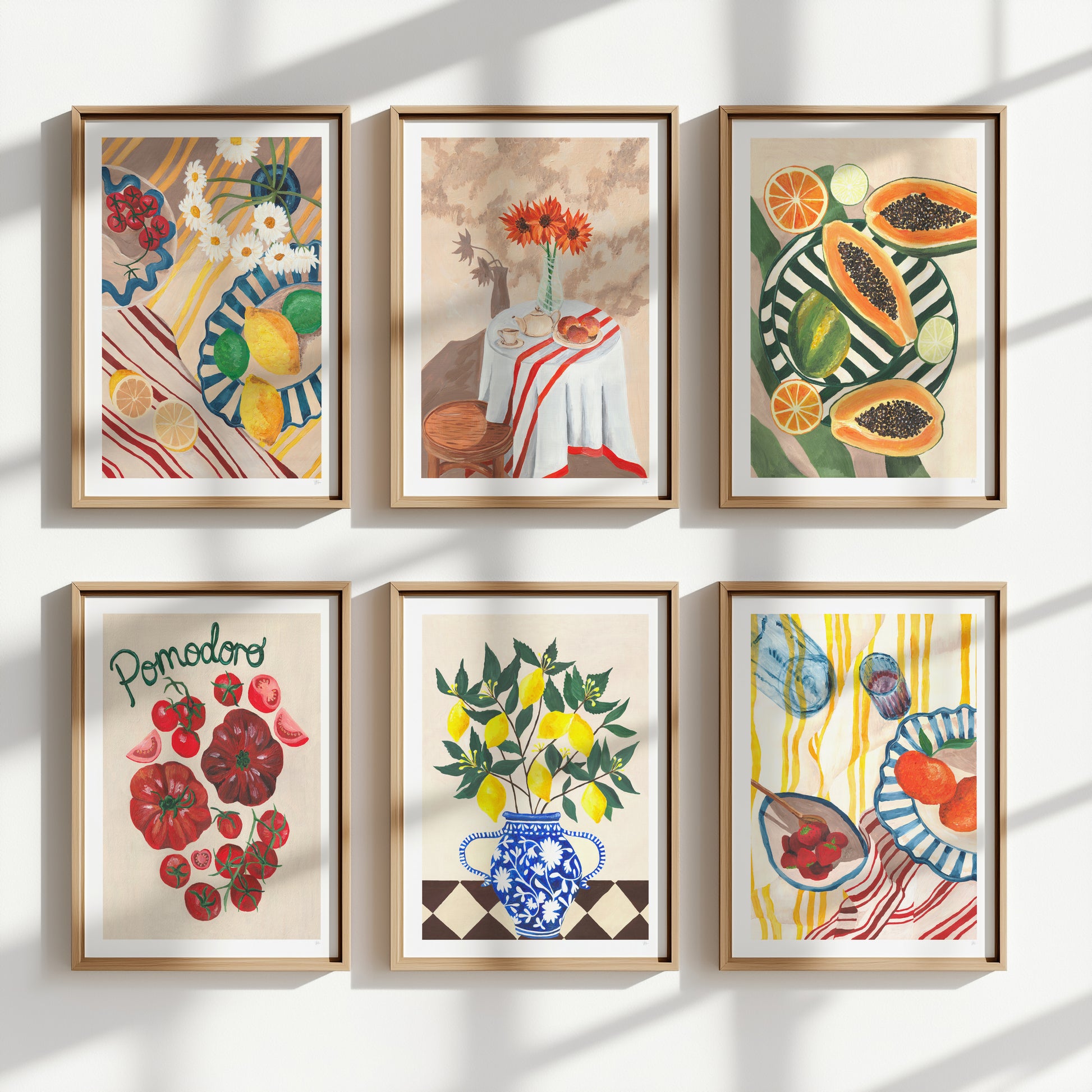 Set of six framed artworks depicting still life scenes with fruits and flowers on a wall.