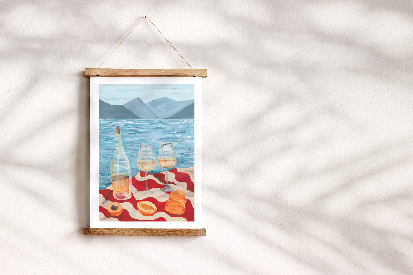 Framed artwork of a scenic view with bottles and glasses on a table, hanging on a white wall.