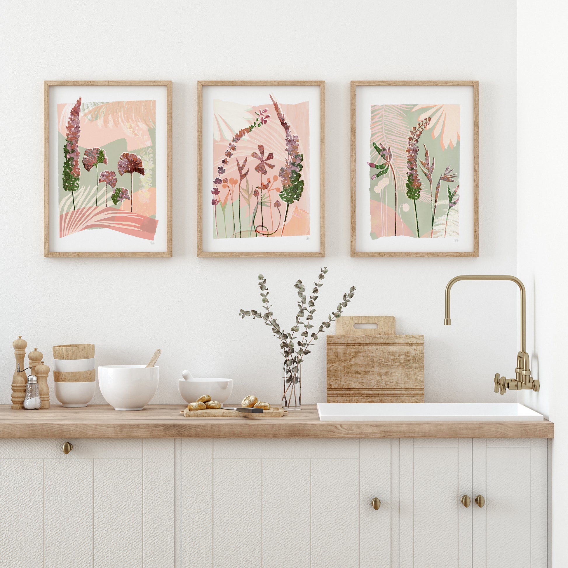 Kitchen with floral prints on the wall, wooden countertop, and white cabinets.