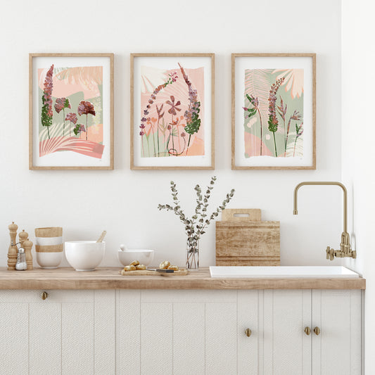 Kitchen with floral prints on the wall, wooden countertop, and white cabinets.