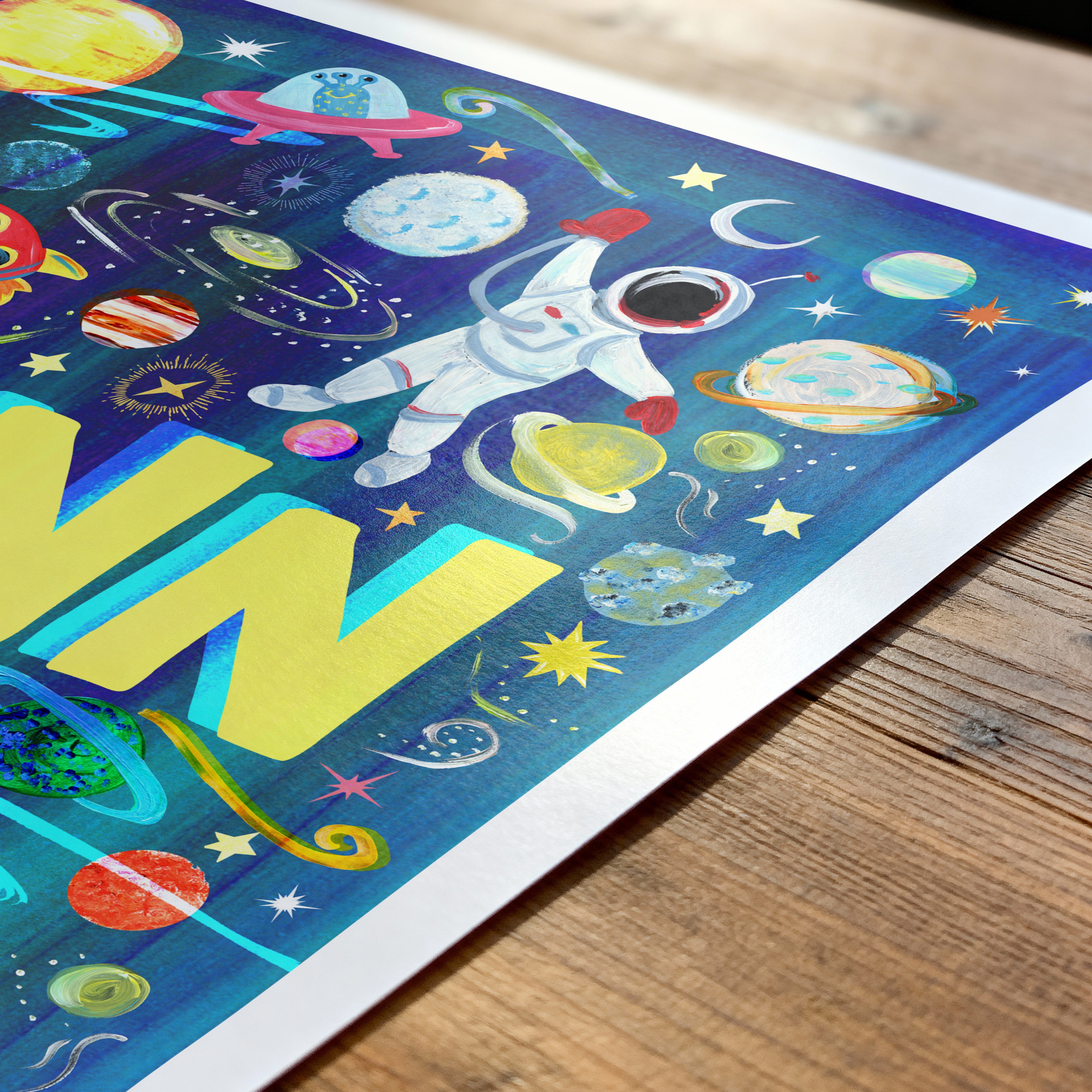Colorful space-themed poster with an astronaut and planets on a wooden surface