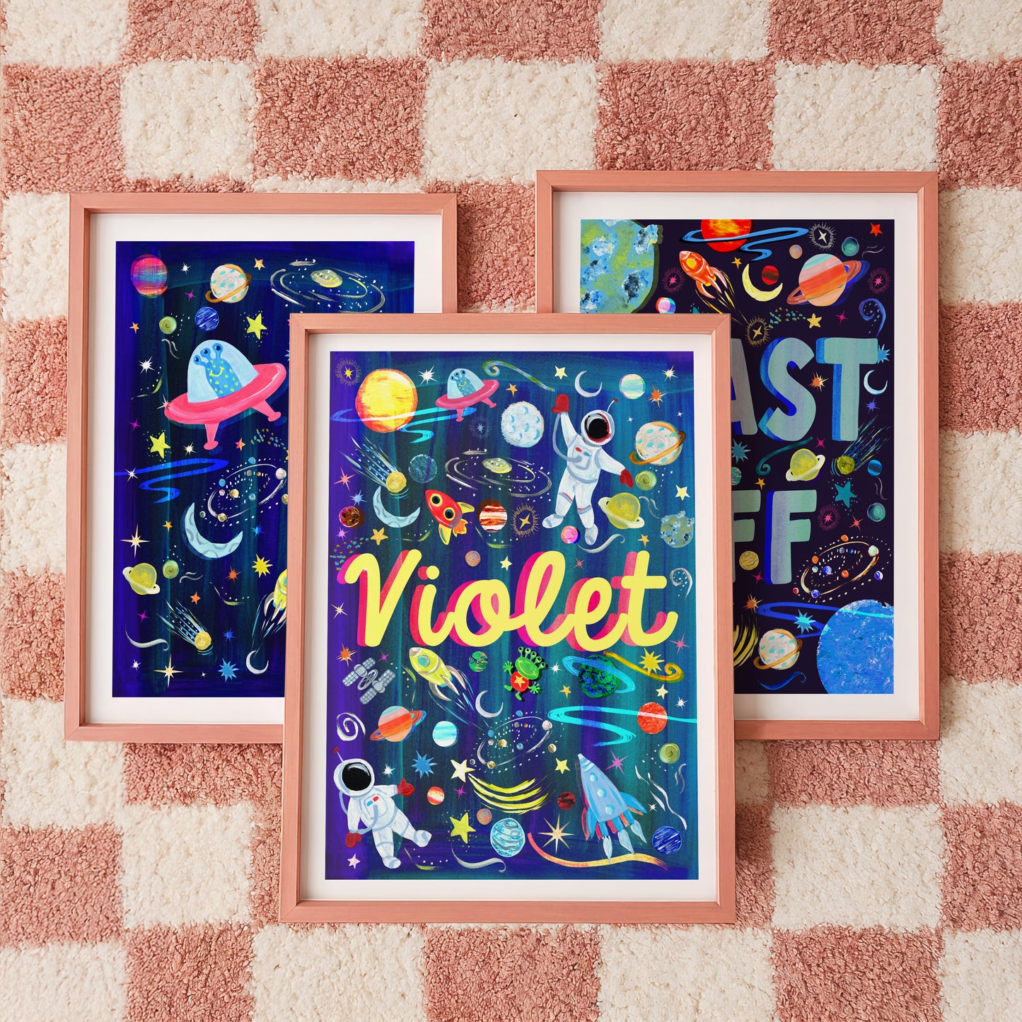 Three framed space-themed artworks on a checkered wall.