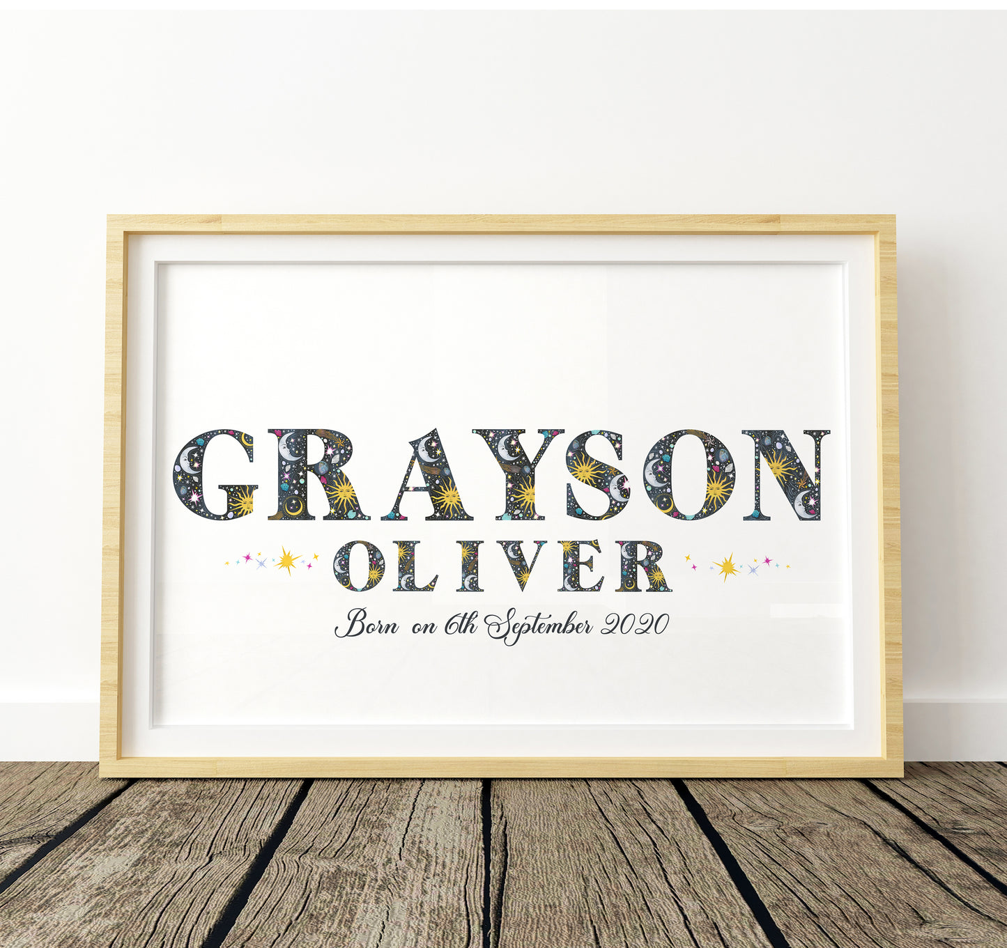 Framed print with name and birth date with sun, moon and star illustrations on a white background