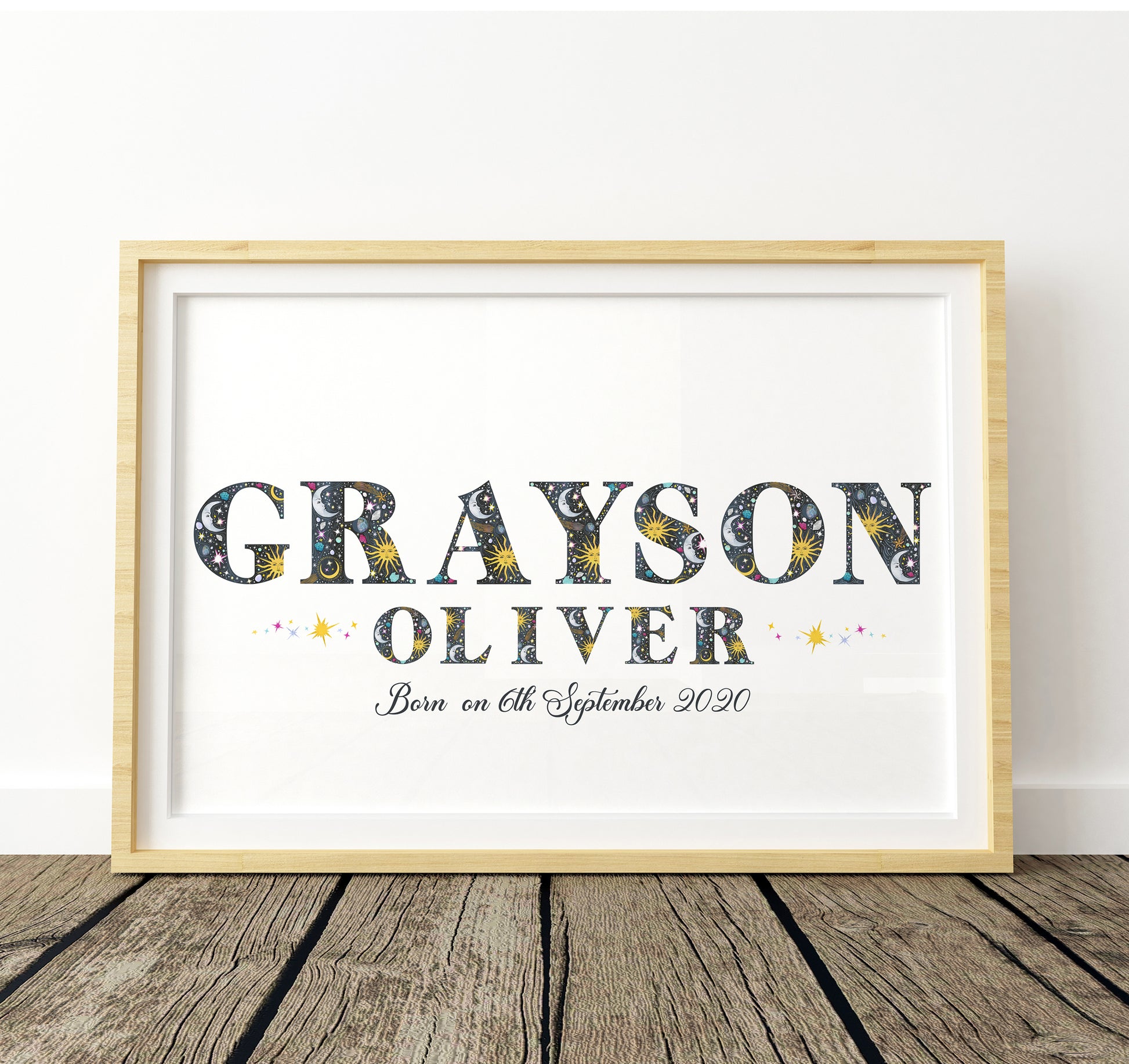 Framed print with name and birth date with sun, moon and star illustrations on a white background