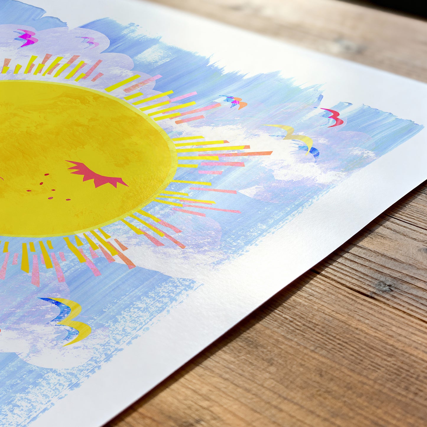 Colorful sun and cloud illustration on a wooden surface