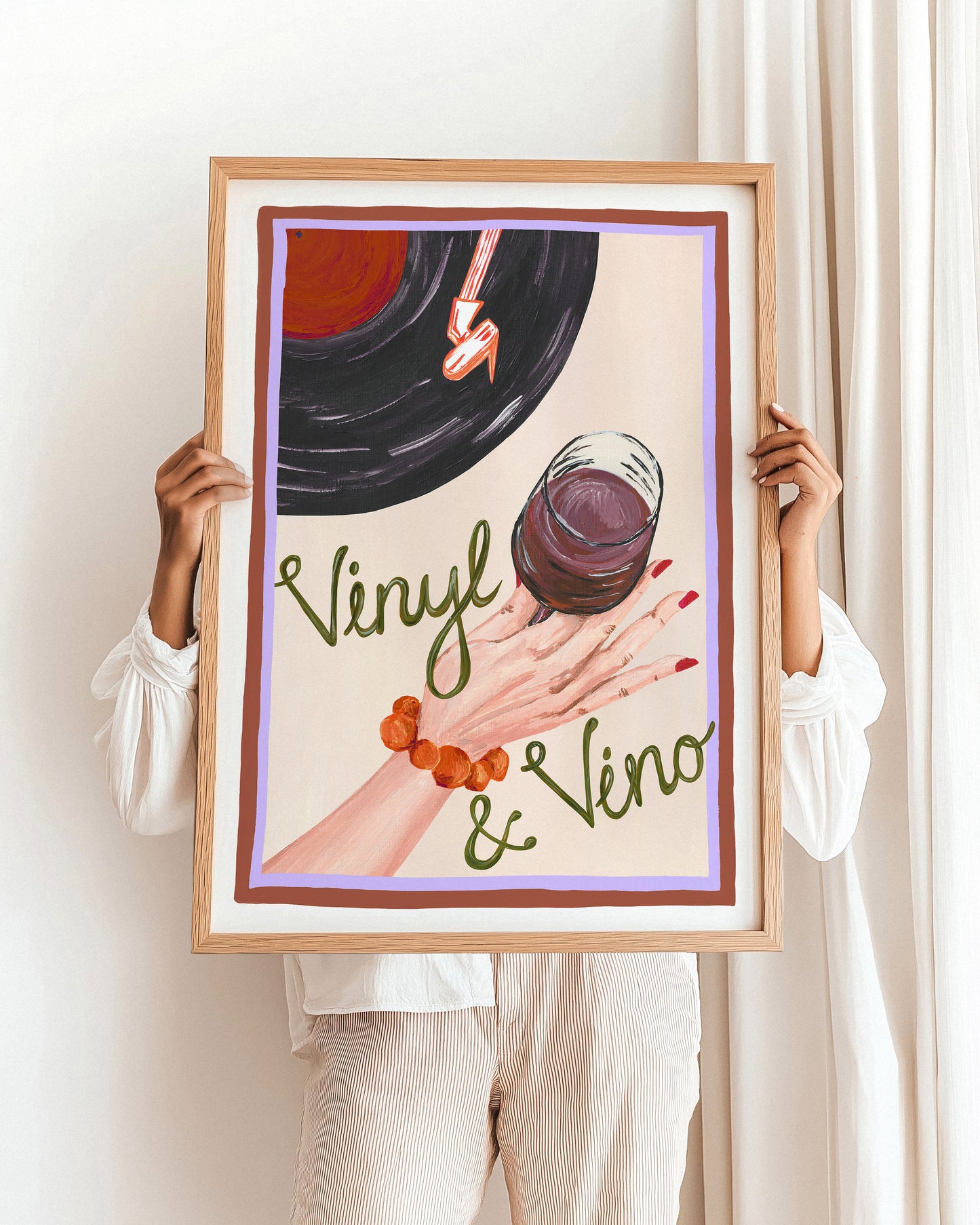 Person holding a framed artwork with a vinyl record and glass of red wine.
