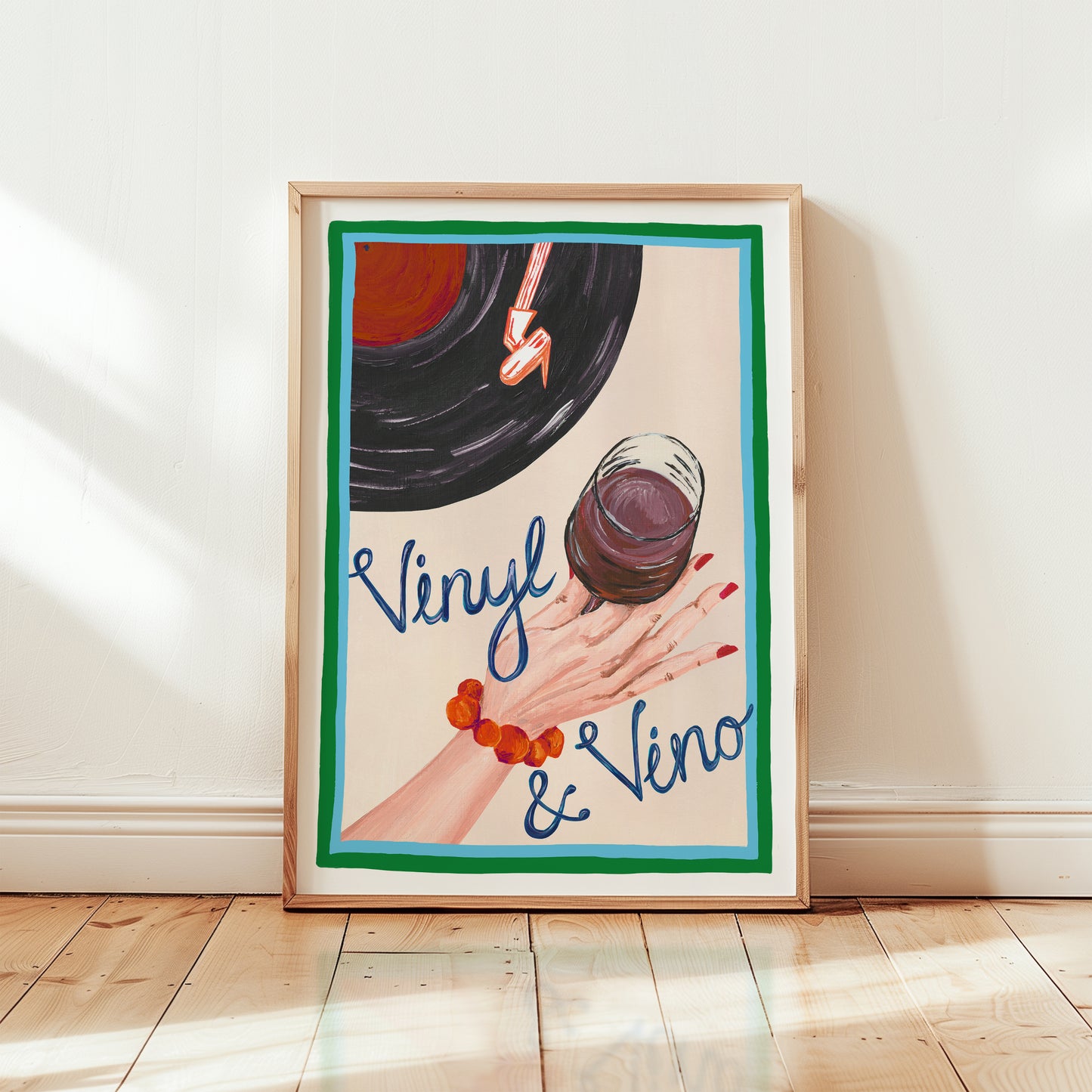 Framed artwork with a hand holding a glass of red wine and a vinyl record, text 'Vinyl & Vino' on a light background.