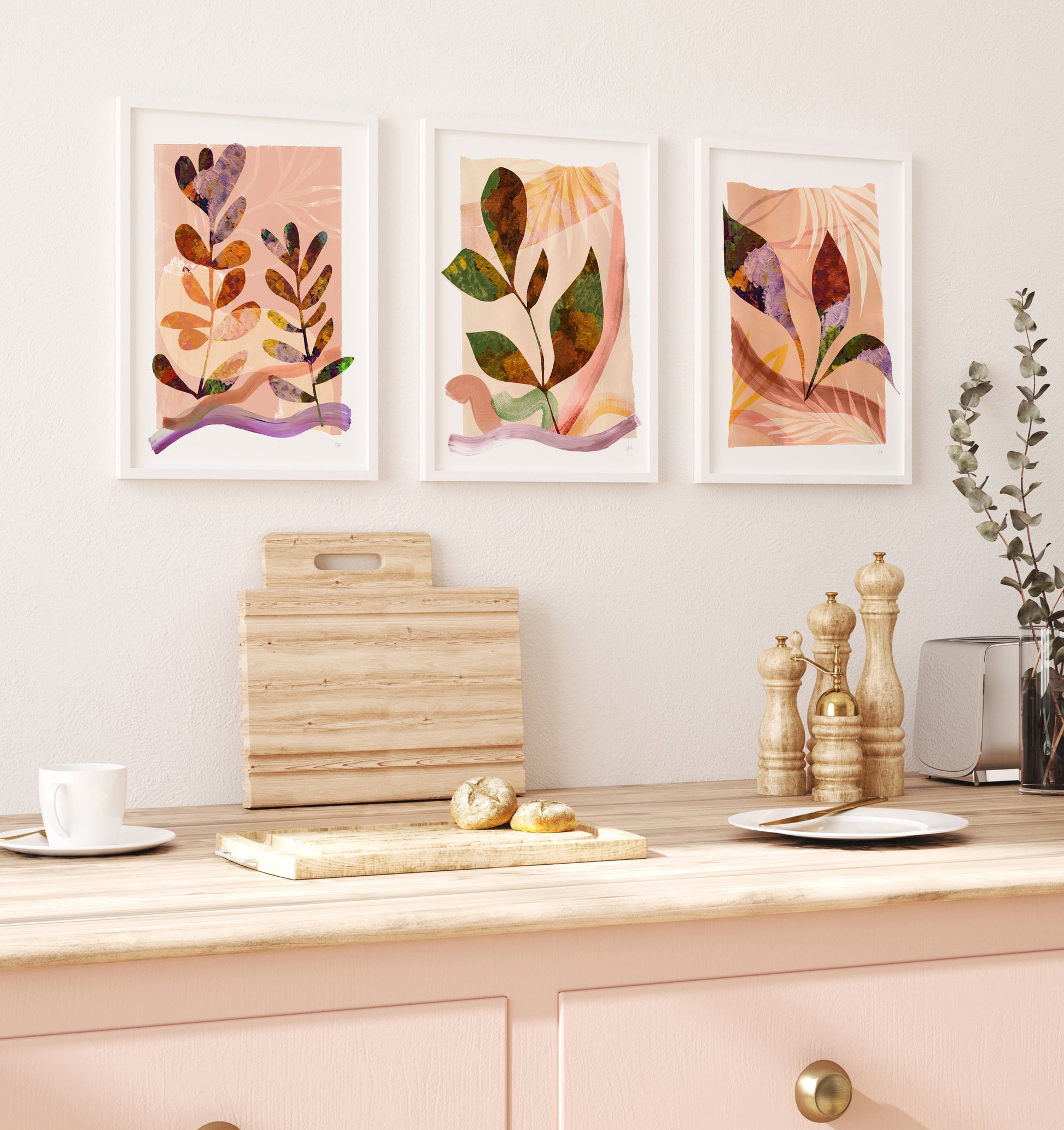 Three abstract wall art prints on a kitchen wall with wooden cutting boards and kitchen utensils.