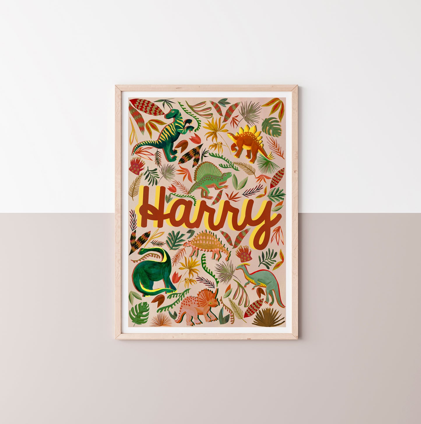 Framed artwork with colorful dinosaur illustrations and the name 'Harry' on a white wall.