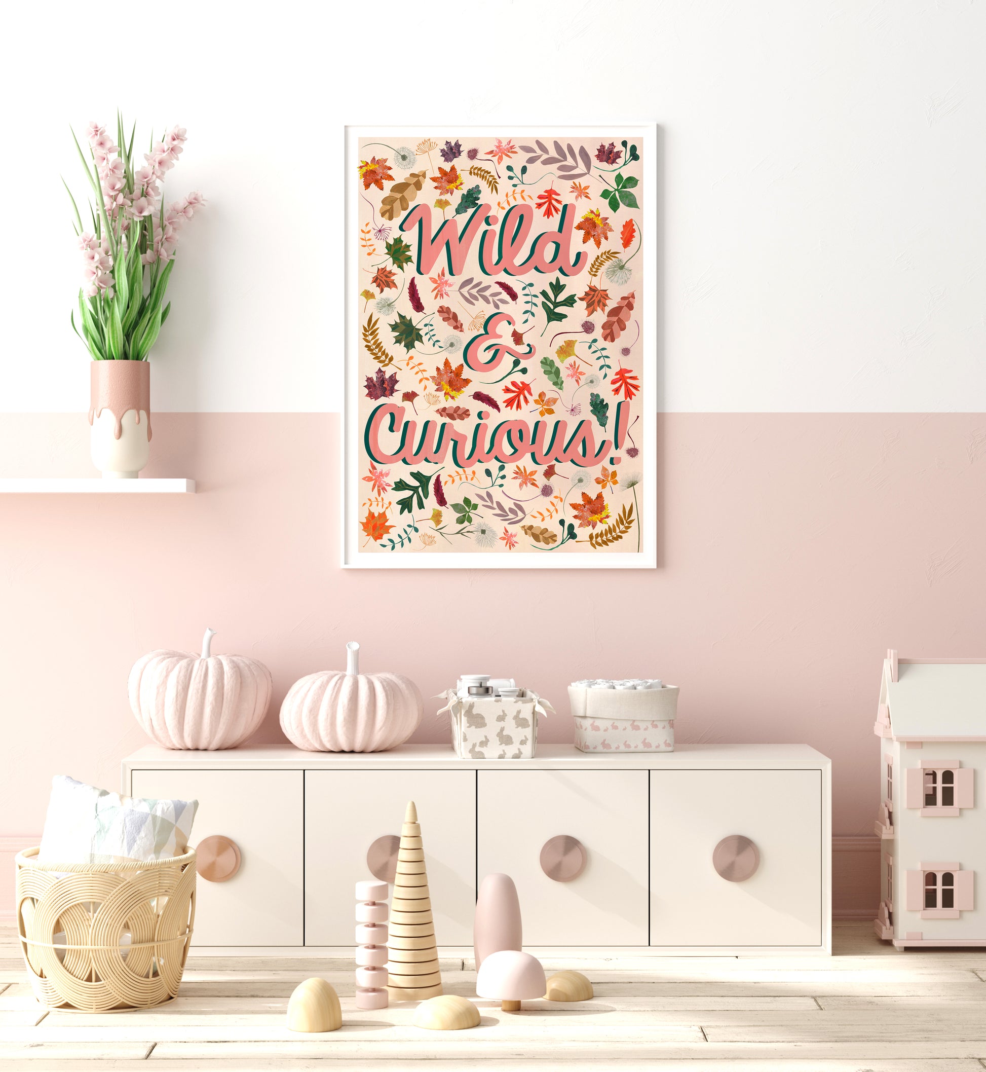 Decorative poster with 'Wild & Curious' text in a colorful frame on a pink wall.